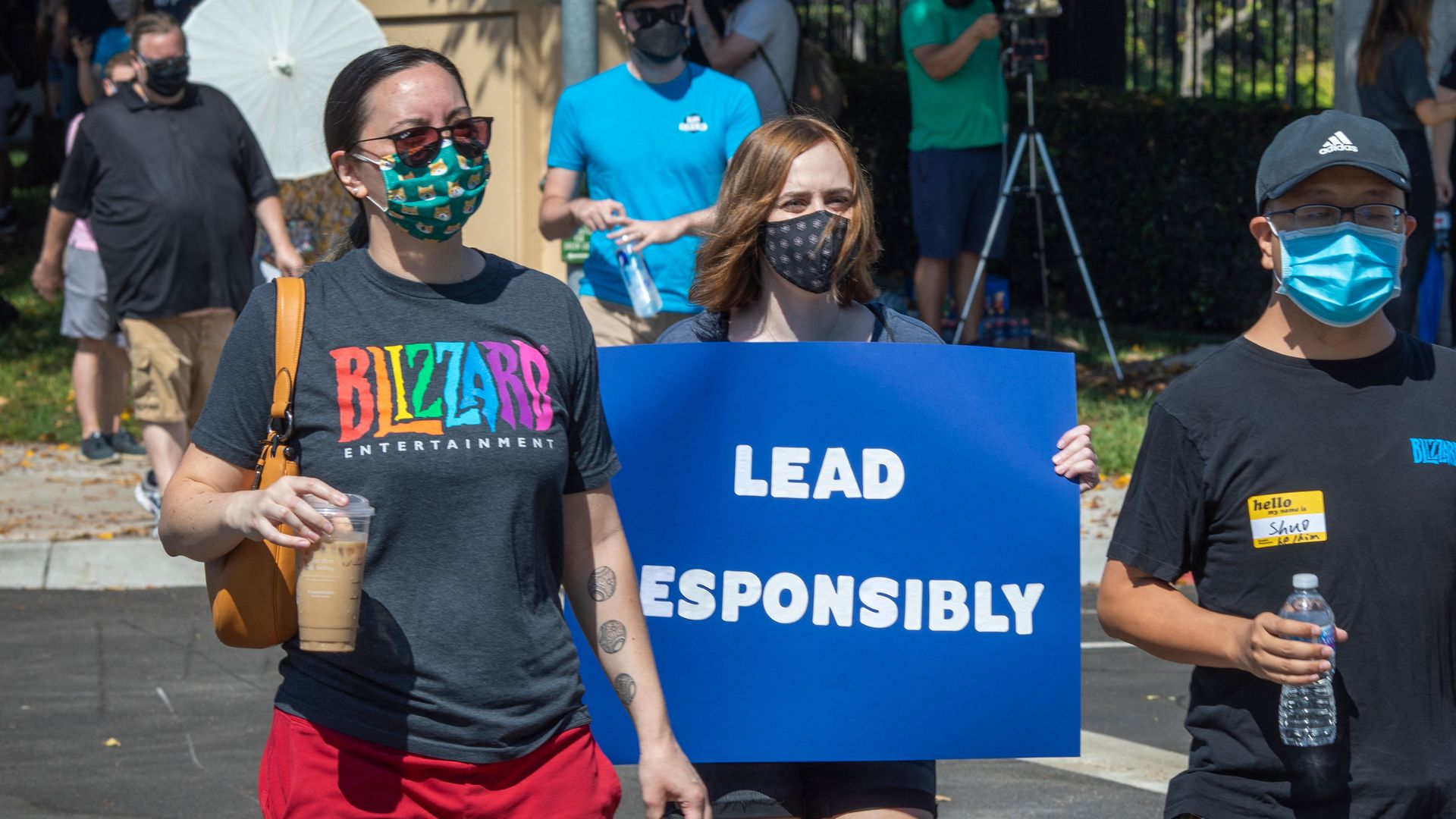 Photo of women protesting. One wears a shirt with the Blizzard logo on it. The other holds a sign that says "Lead Responsibly"