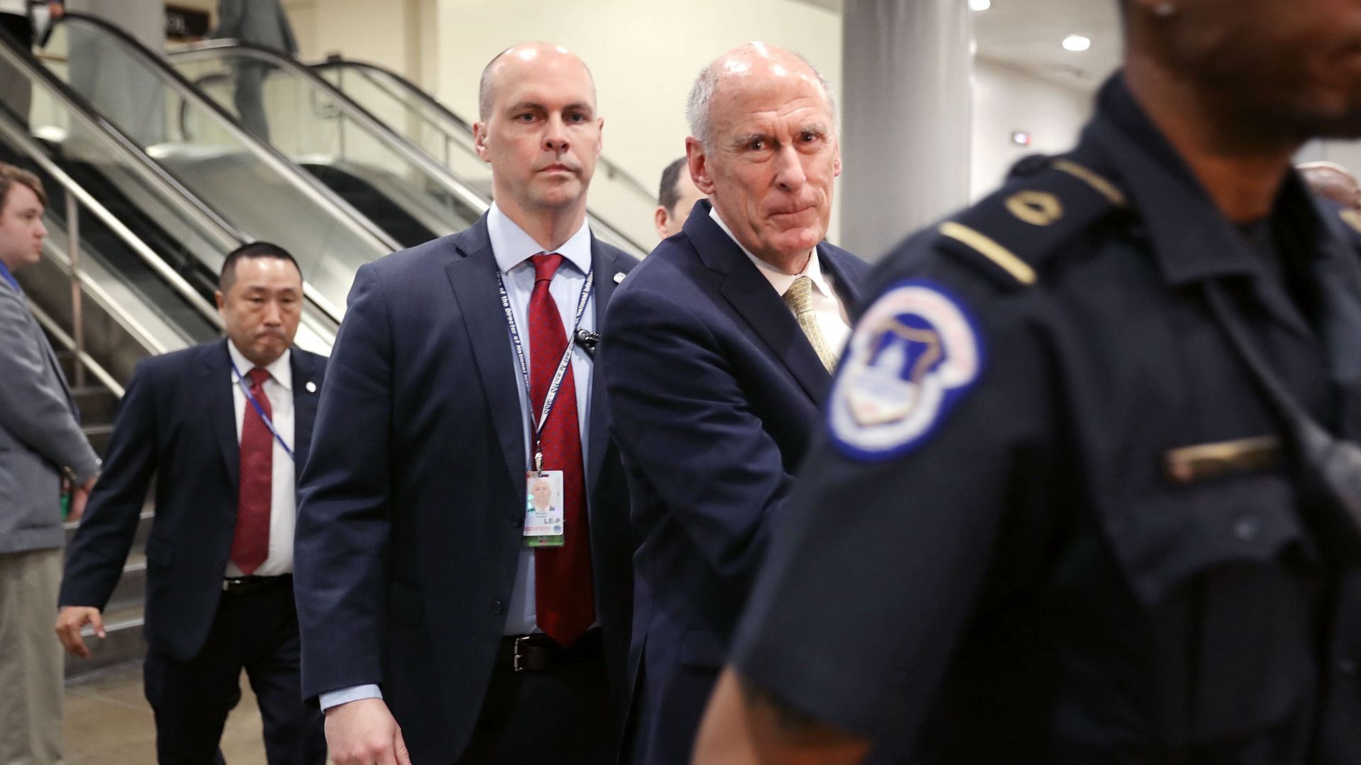 Director of National Intelligence Dan Coats walking through a hallway surrounded by security