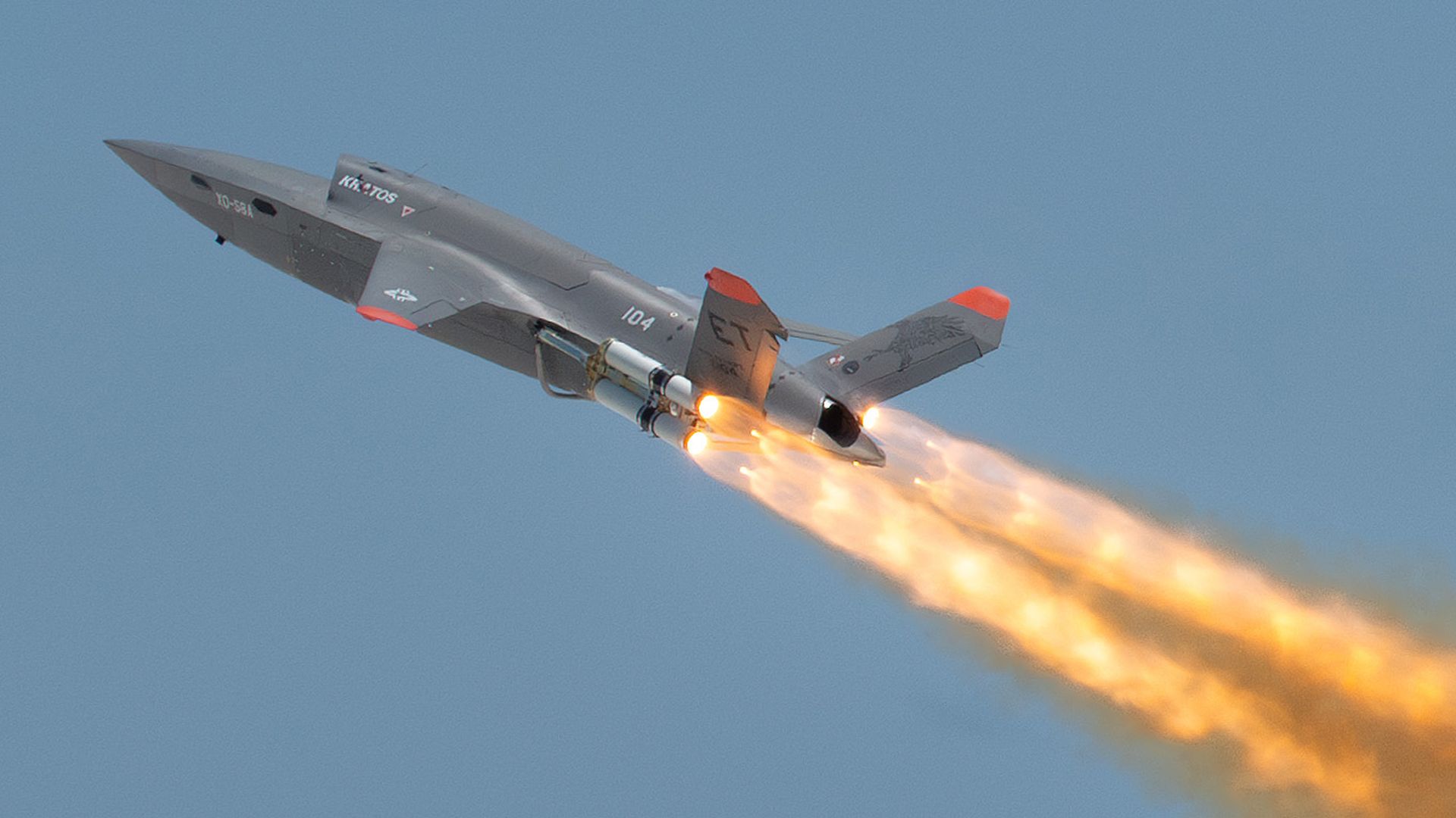 A large drone rockets through the sky, with orange-and-brown trails of fire shooting behind it.