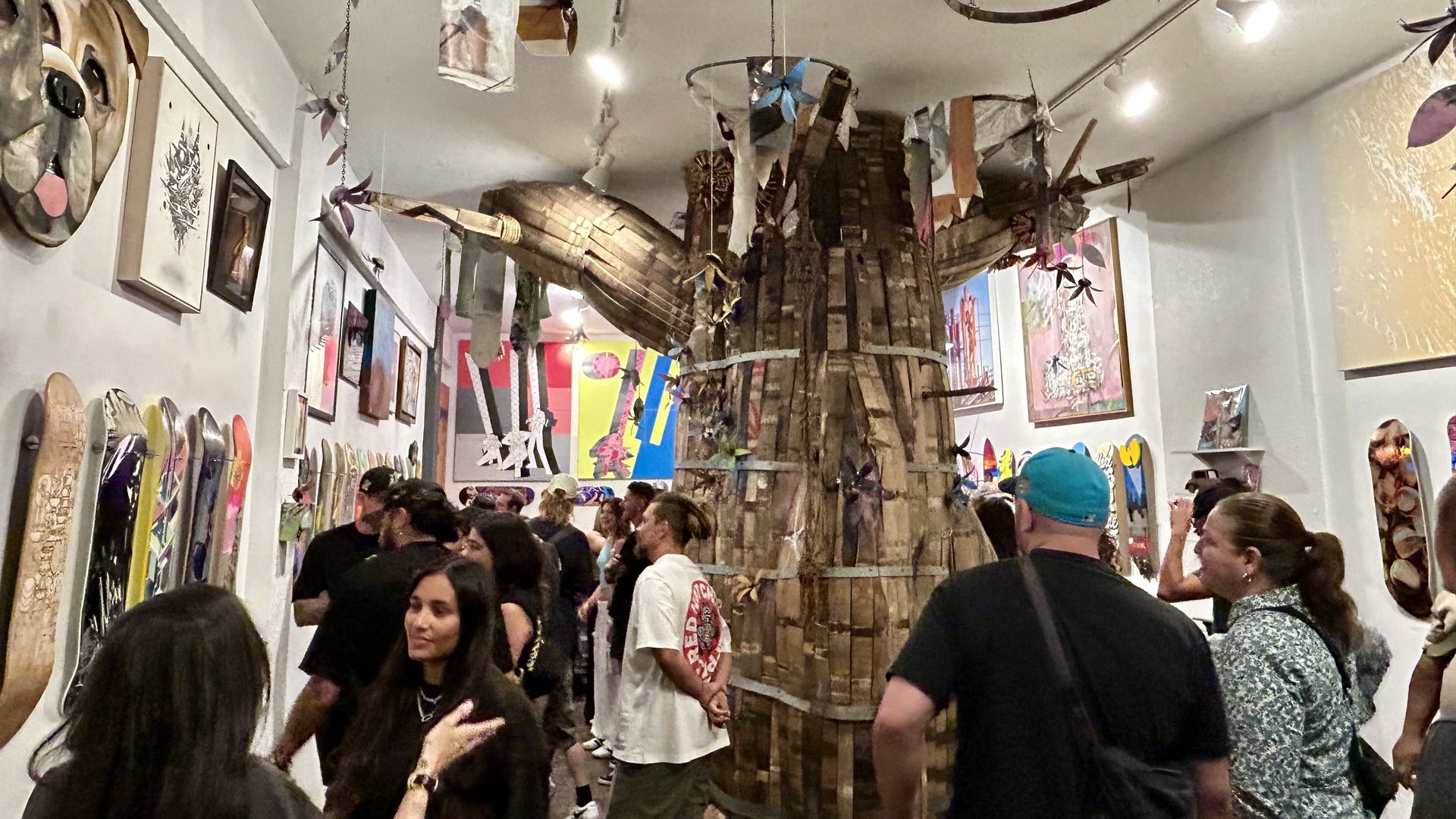 A group of people looking at art with a structure in the middle of the room.