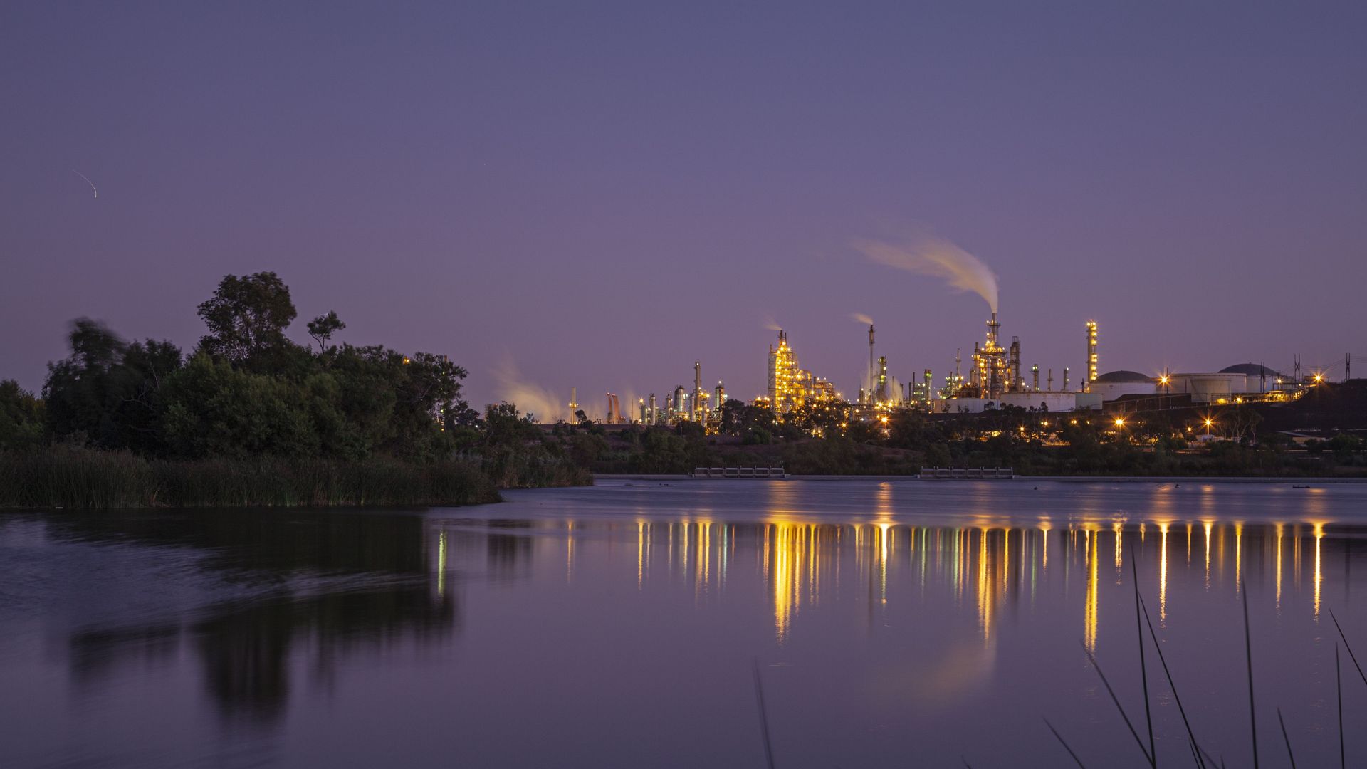 Oil refinery seen at night, reflected in water.