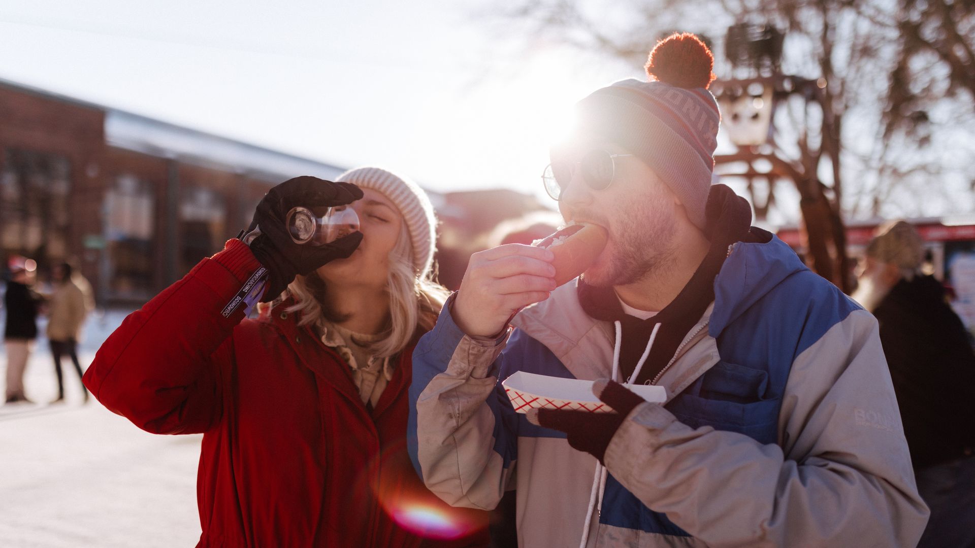 A woman drinking beer and a man eating a hot dog on a sunny winter day at the Minnesota State Fairgrounds.