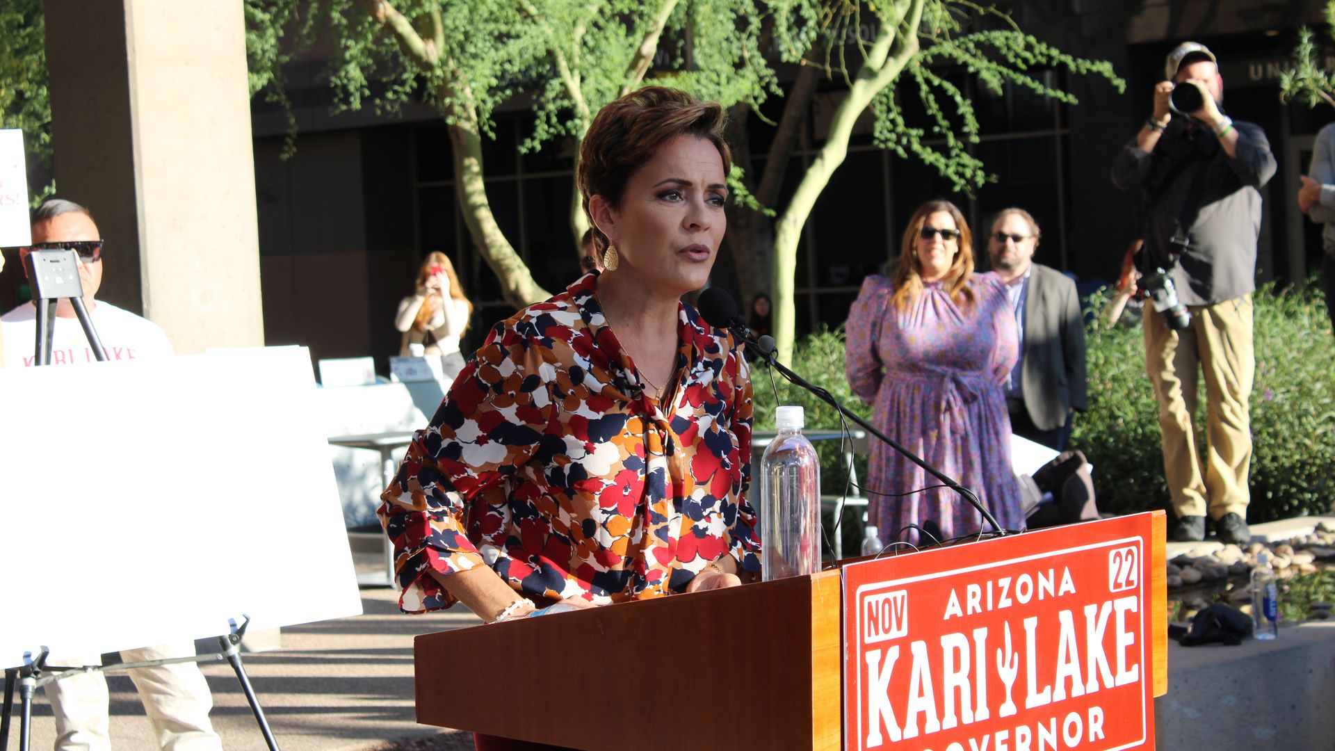 Kari Lake speaks at a lectern with her campaign sign on the front