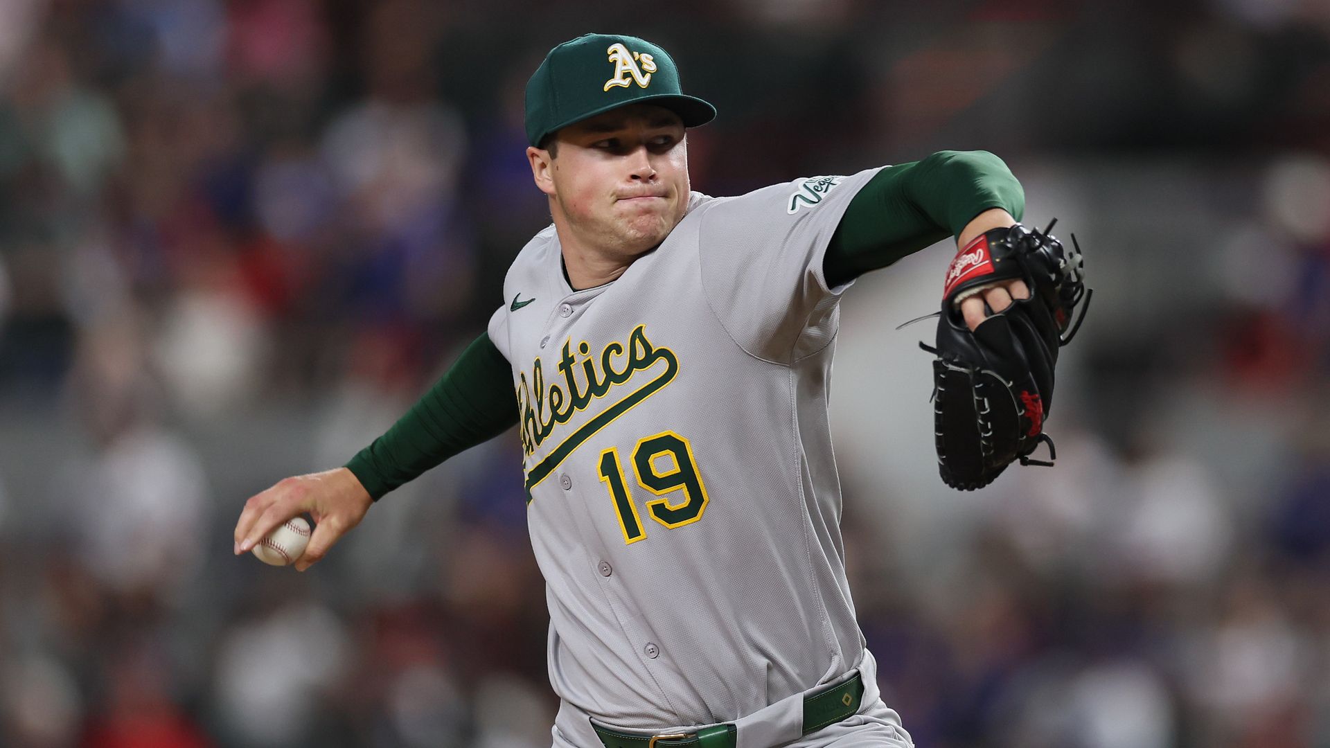 Mason Miller throwing a pitch in a green A's jersey