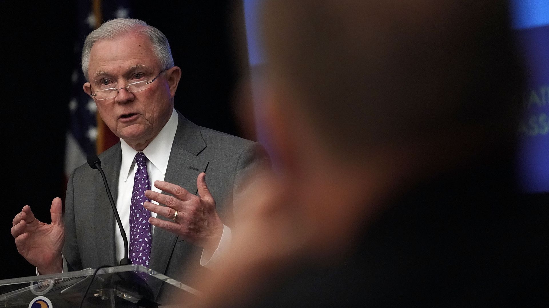 Attorney General Jeff Sessions speaks from a podium, wearing a suit