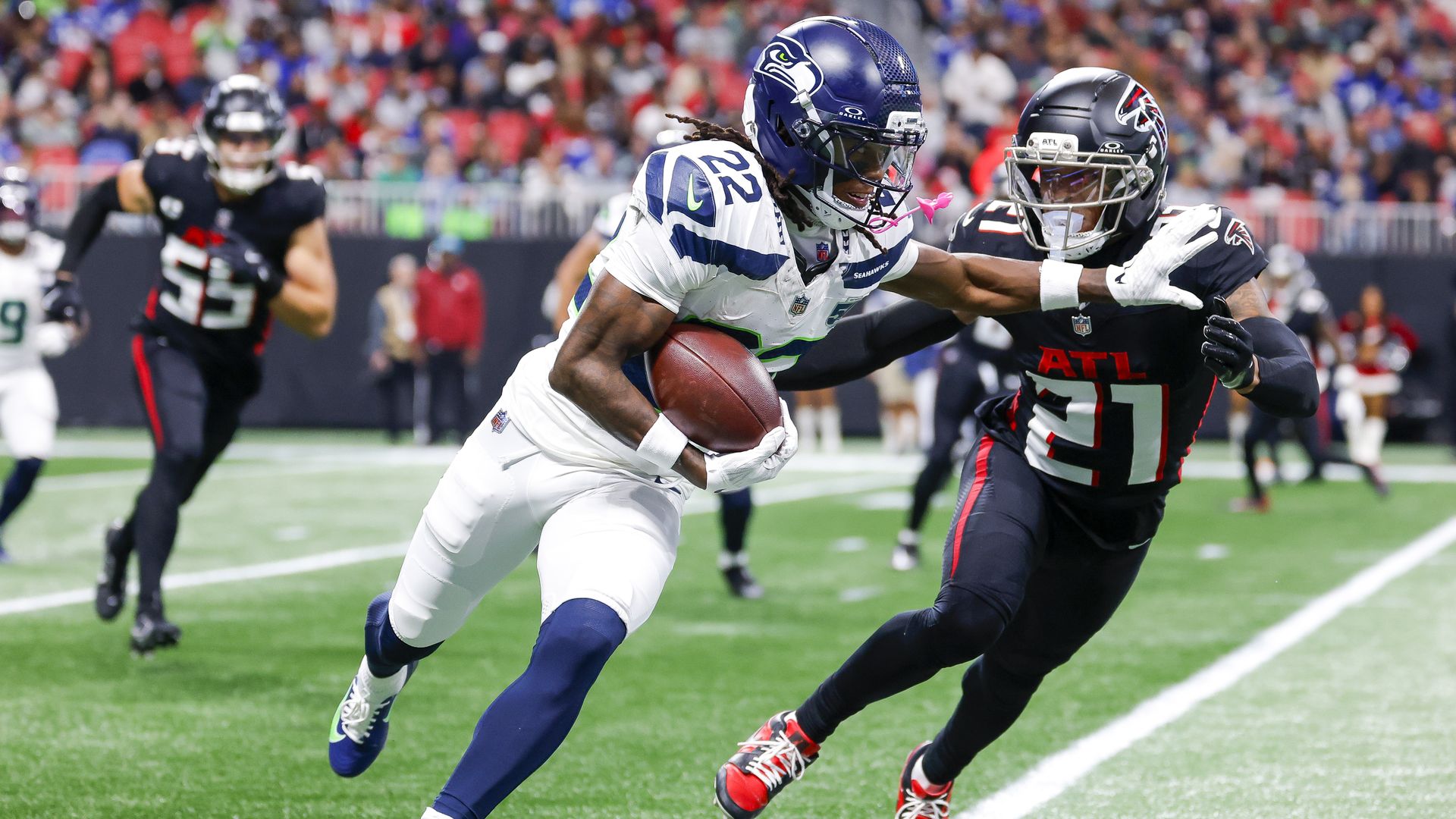A Seahawks running back carries the ball up the sideline while stiff-arming a Falcons defender during Seattle's win in Atlanta.