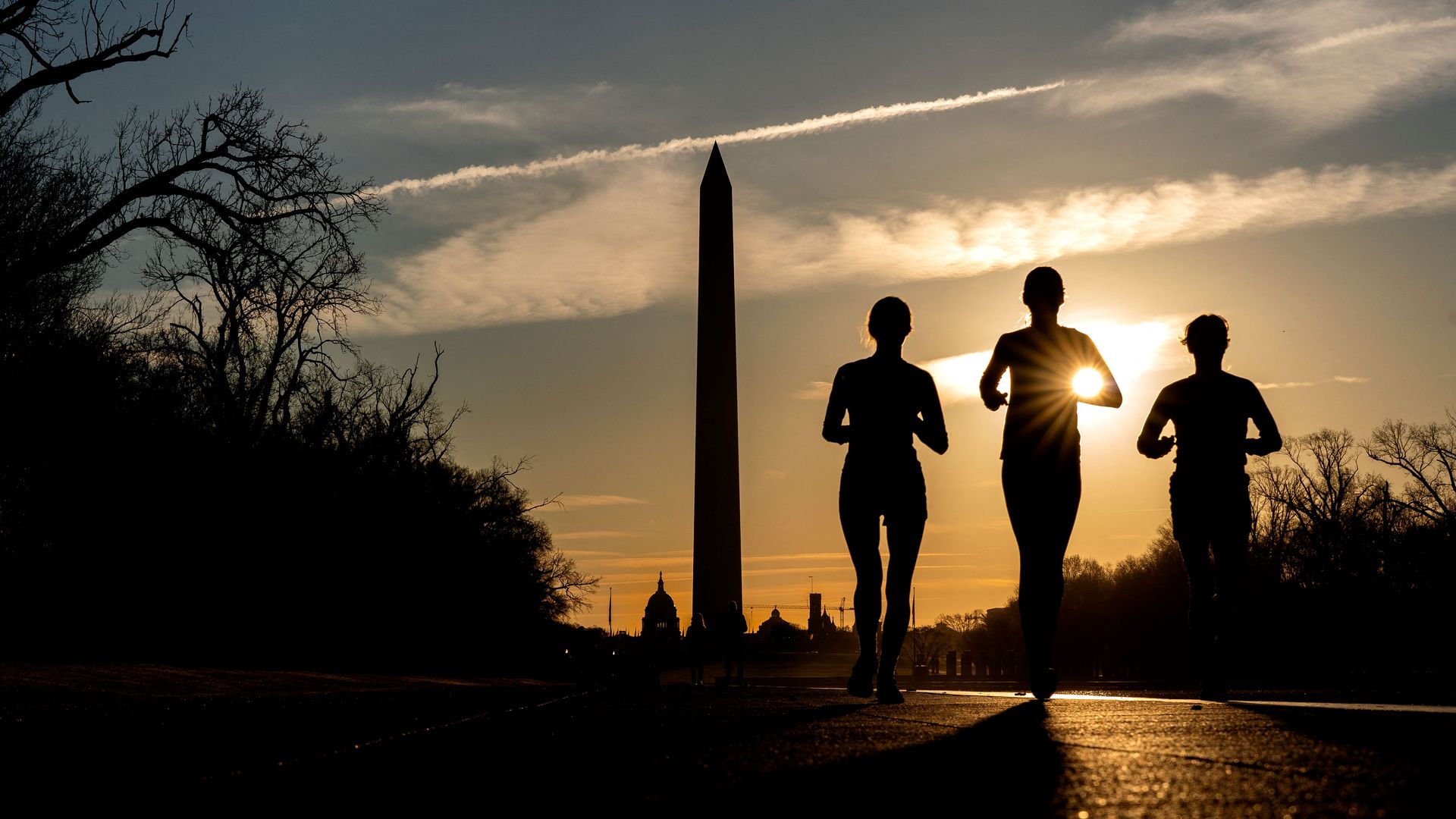 Joggers are seen at sunrise running alongside the Reflecting Pool.