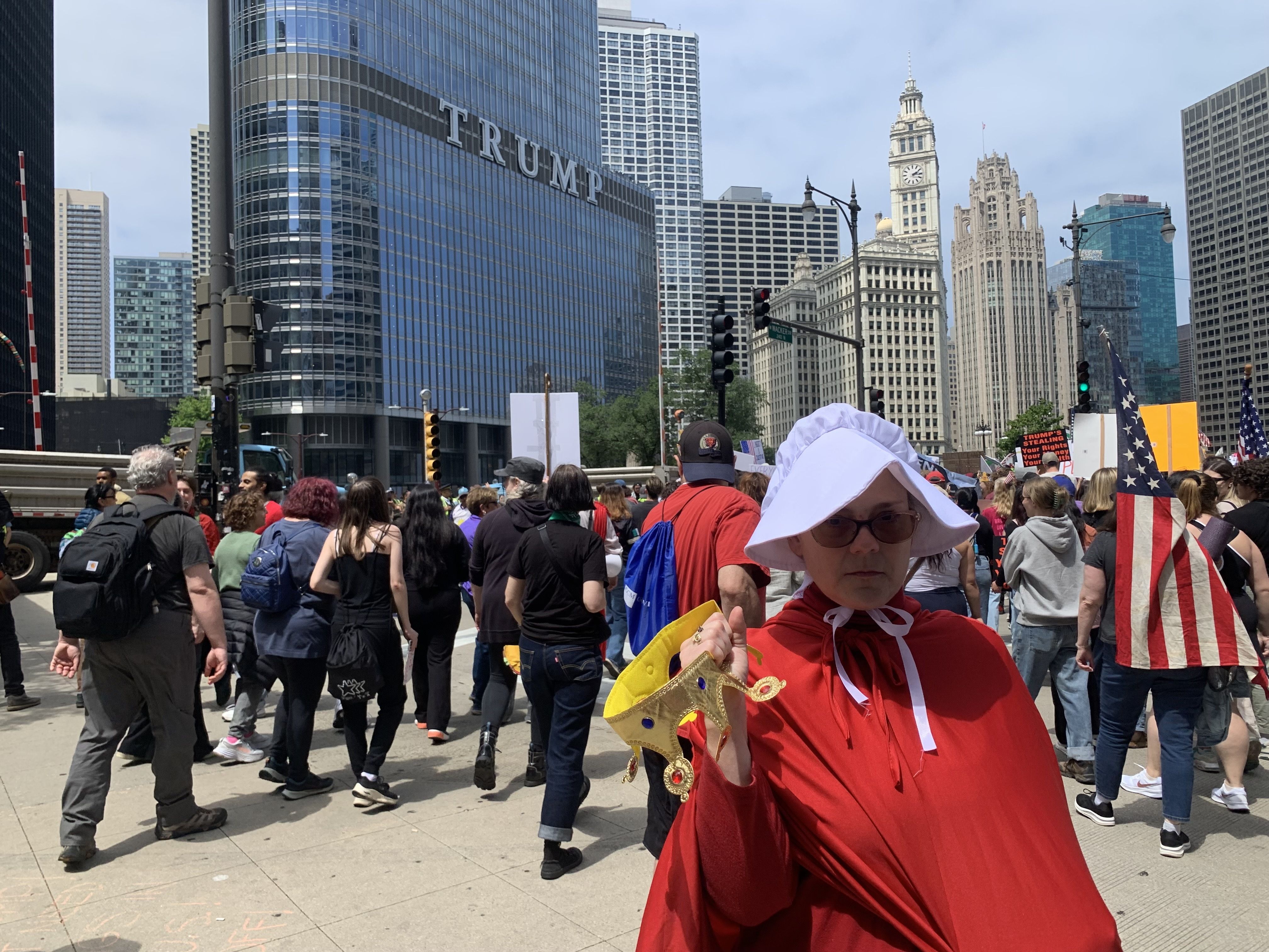 Protesters fill up a plaza with signs and march on a street. 