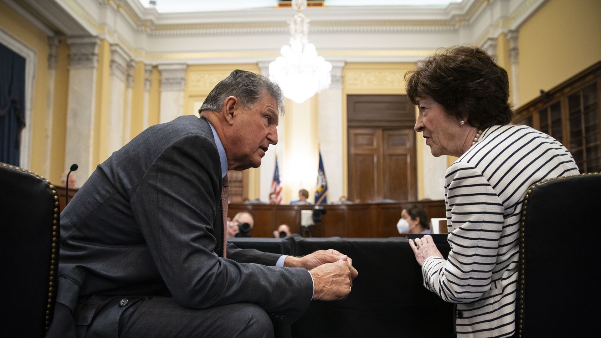 Sens. Joe Manchin, wearing a gray suit, and Susan Collins, wearing a white and black striped sweater, speak at a committee hearing.