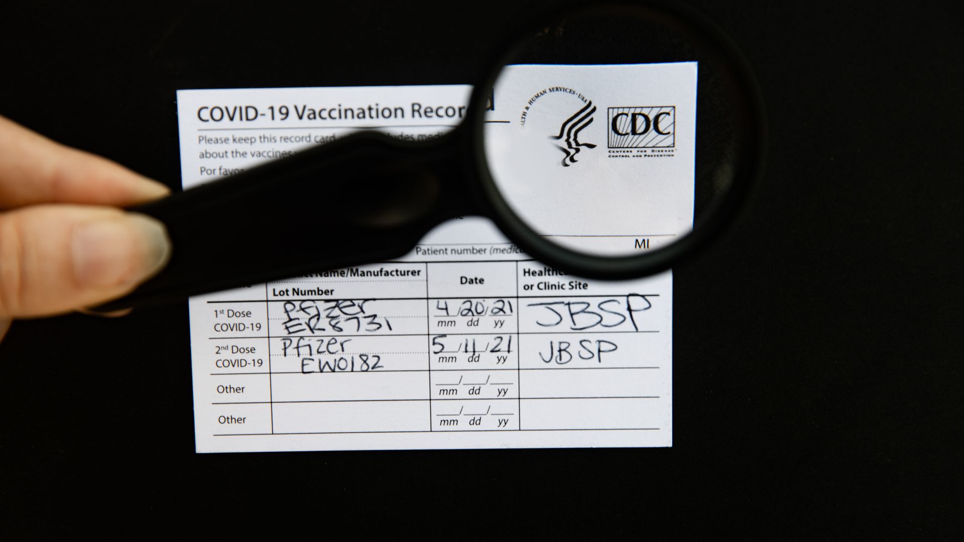 A covid-19 vaccine card with a magnifying glass over the CDC logo