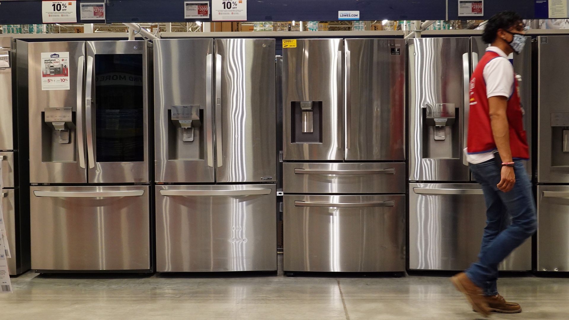 Image of a Lowes employee walking past a line of refrigerators