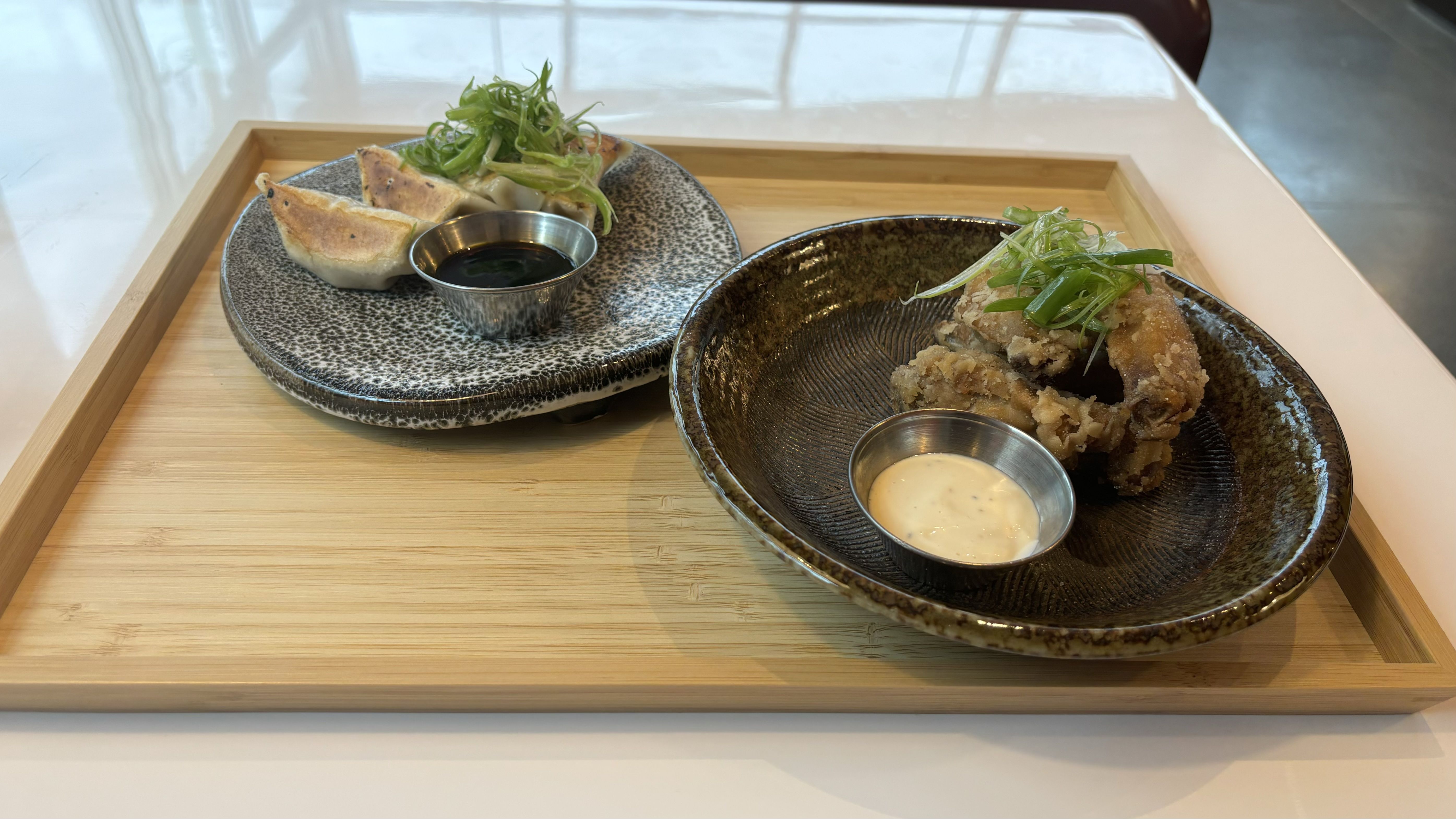 A variety of appetizers, including fried chicken wings and gyoza.