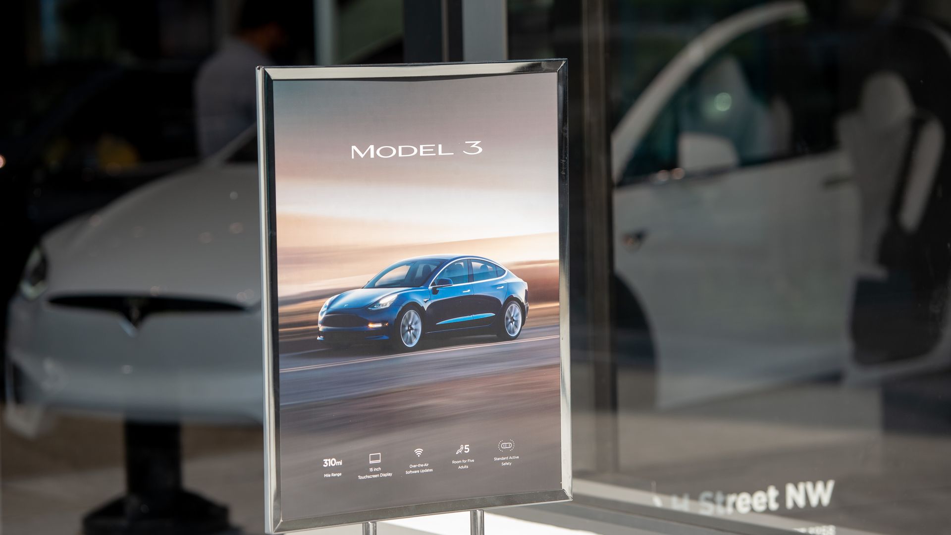 A sign advertisement for the Tesla Model 3 sedan.