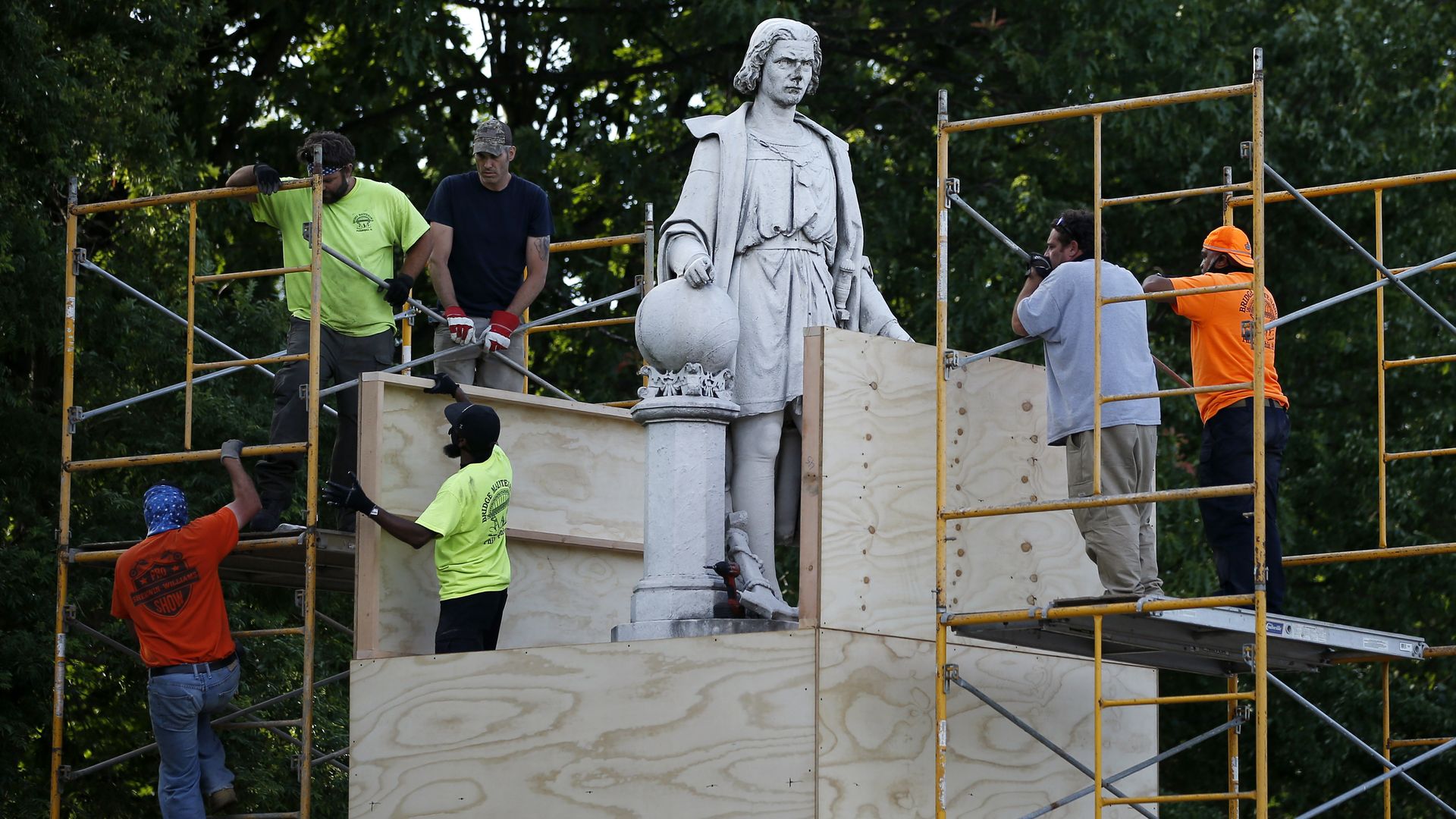 City workers cover the statue of Christopher Columbus at Marconi Plaza.
