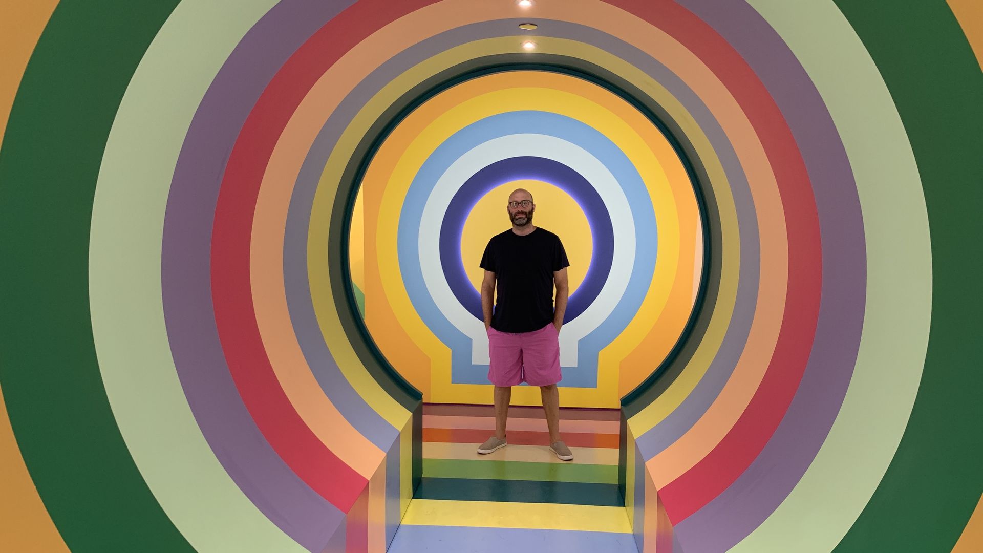 Photo of a man standing inside a colorful cylinder