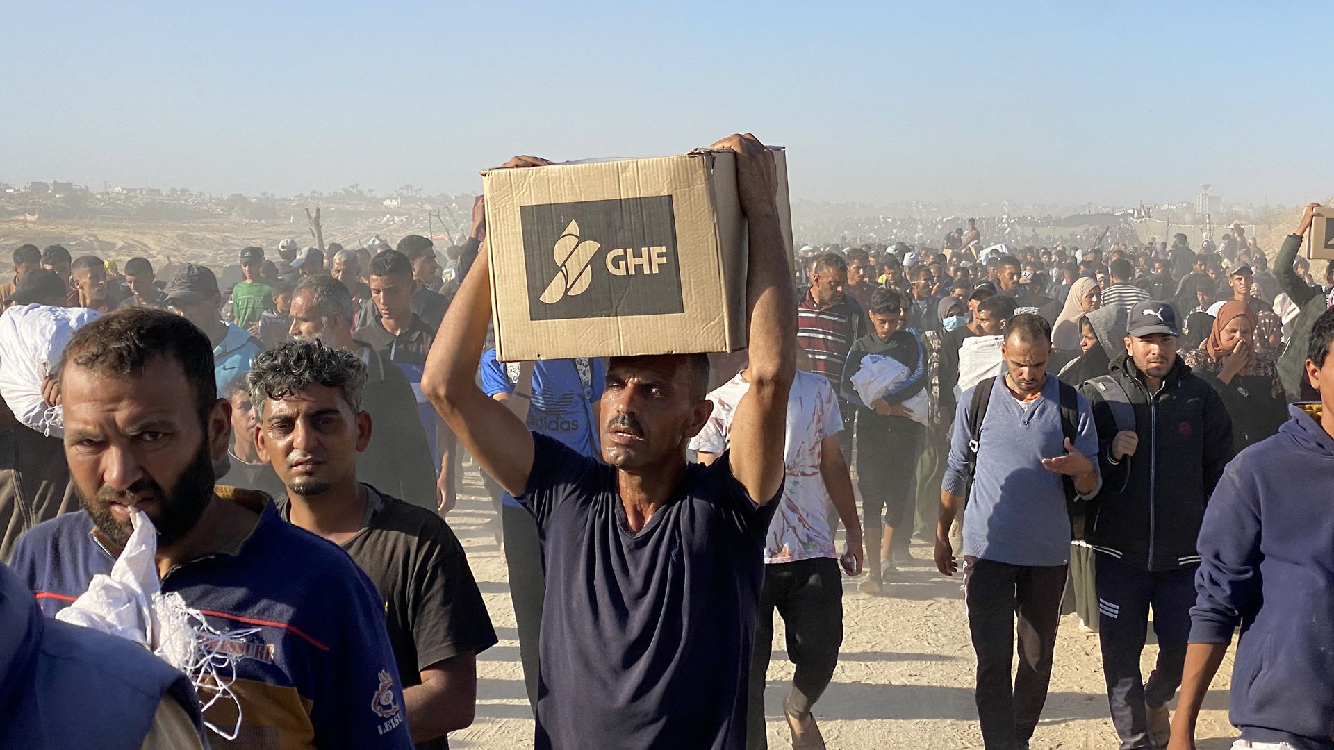 فلسطینی‌ها در حال حمل کمک‌ها از یک مرکز توزیع بنیاد بشردوستانه غزه (GHF). عکس: خبرگزاری فرانسه از طریق گتی ایمیجز