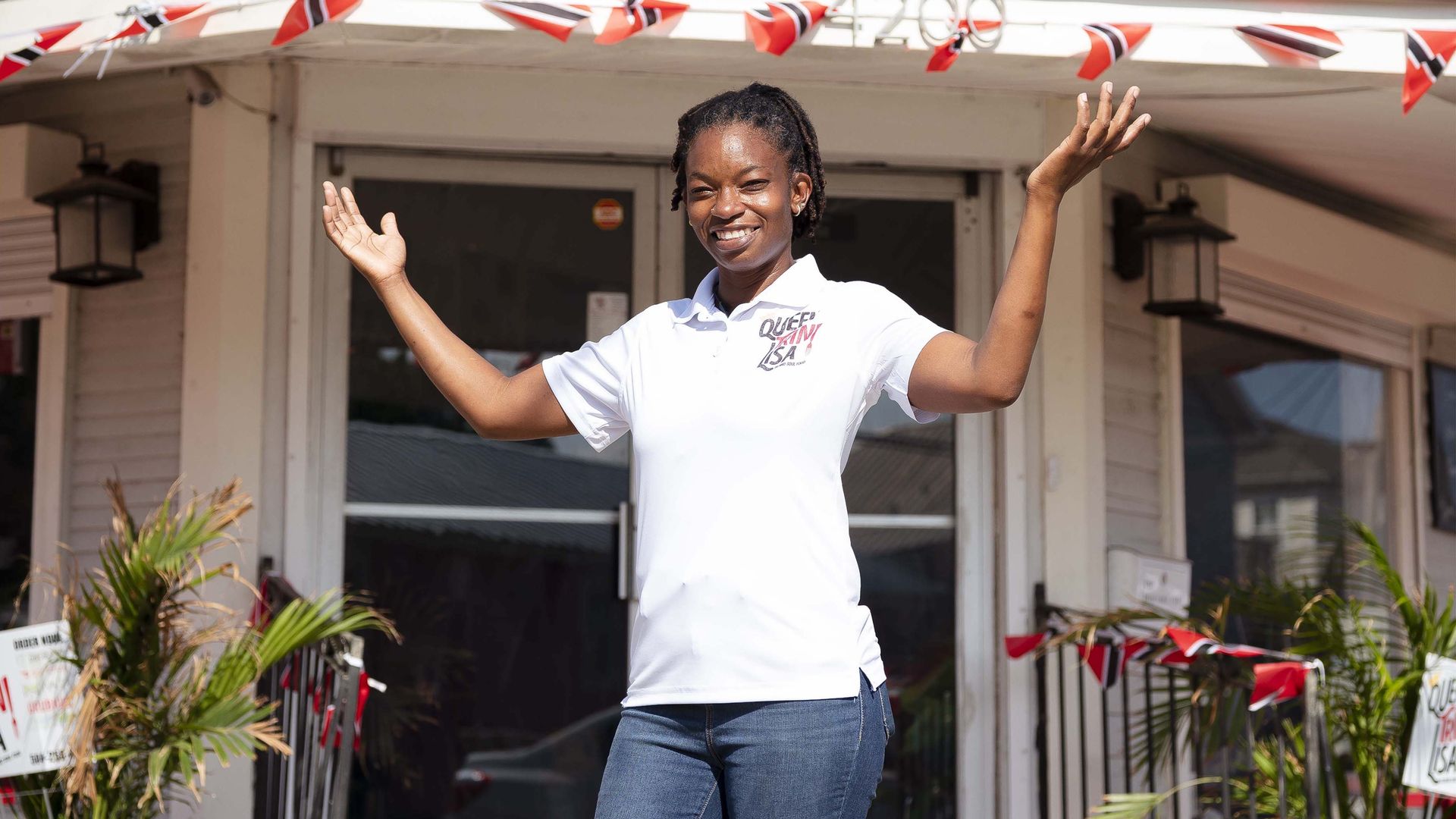Photo shows Queen Trini Lisa standing in front of restaurant and smiling