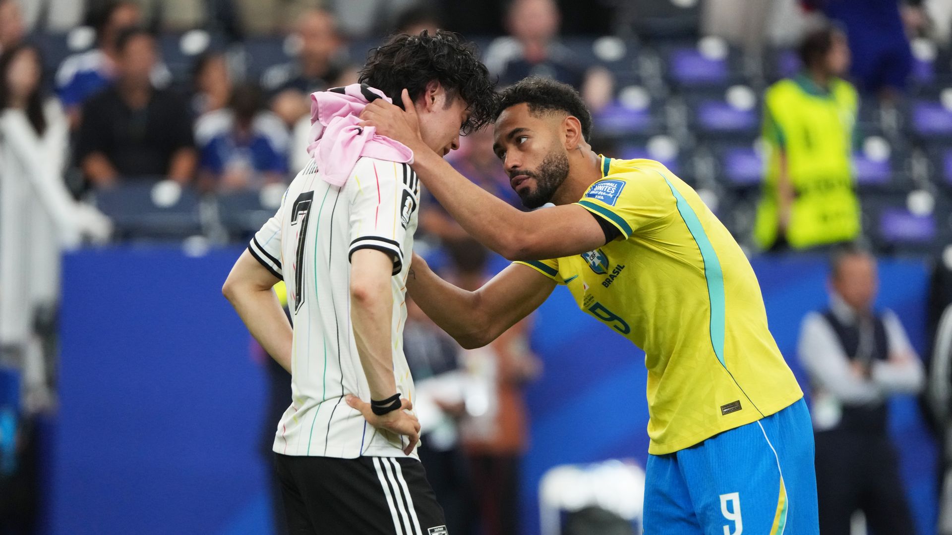 One soccer player in yellow consoling another in white.
