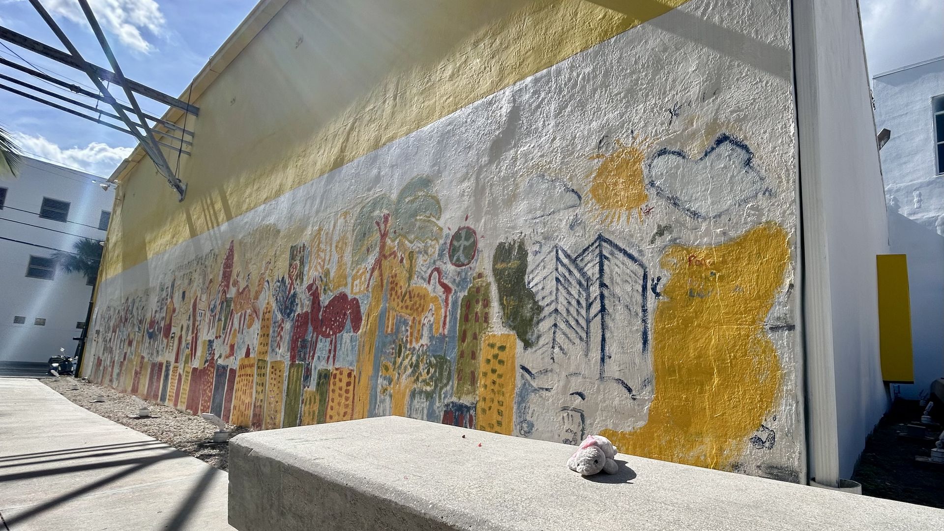 A mural with a manatee stuffed animal in front. 