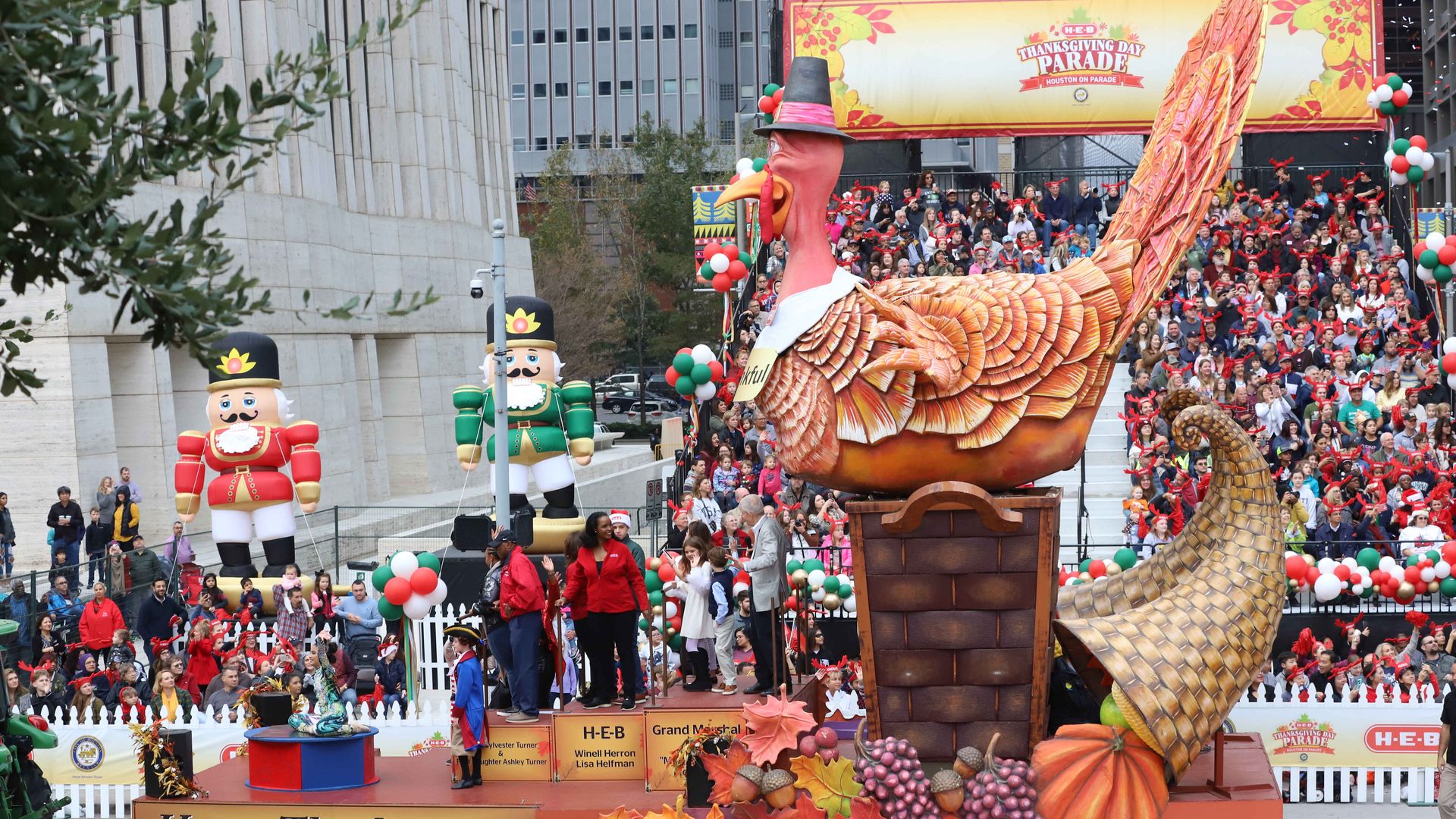 Photo of a turkey float and thousands of people on the sideline. 