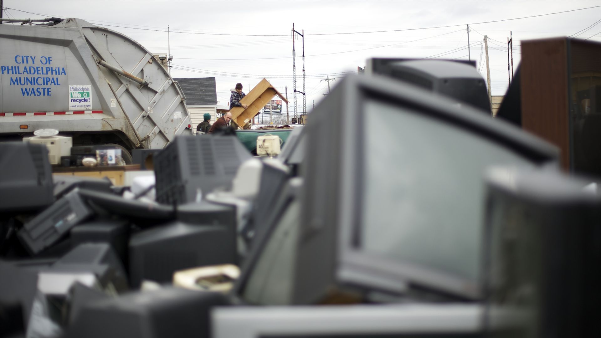 A Philadelphia trash truck near electronic trash, like televisions. 