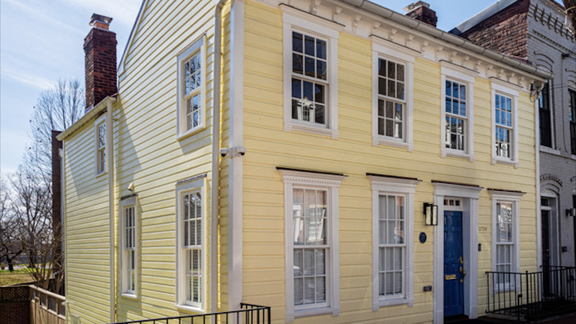 A yellow townhouse with a blue door