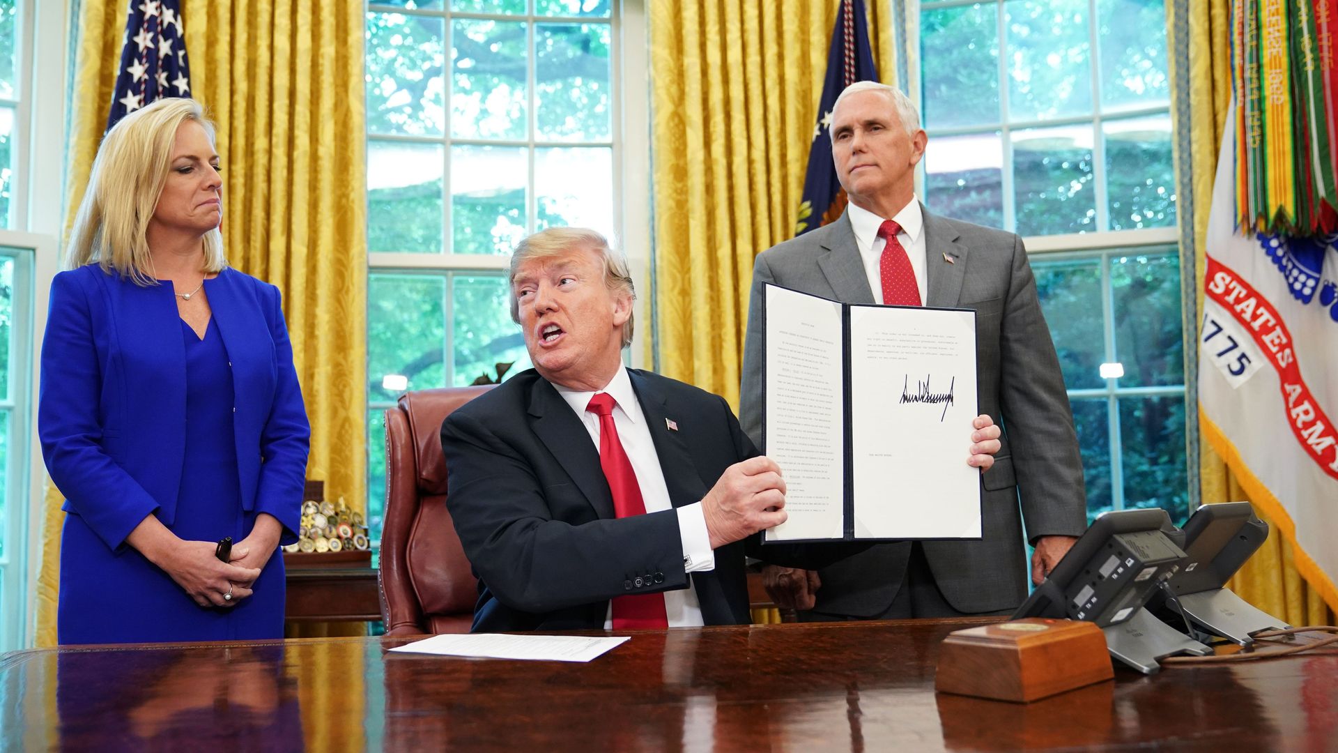 President Trump holding up a signed executive order on immigration