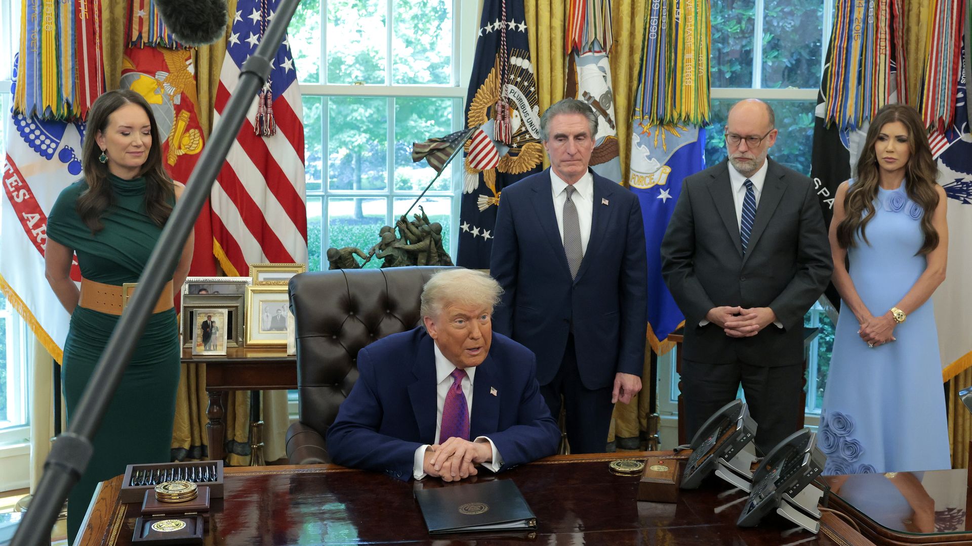Trump speaks in the Oval Office as other members of his administration look on.