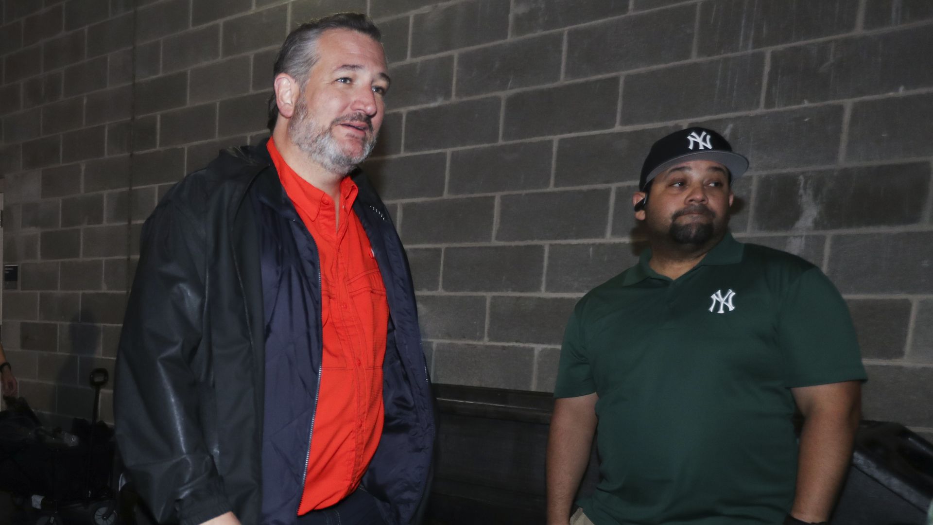 Sen. Ted Cruz, R-Texas, wears an orange shirt and dark coat while walking in the tunnels underneath Yankee Stadium