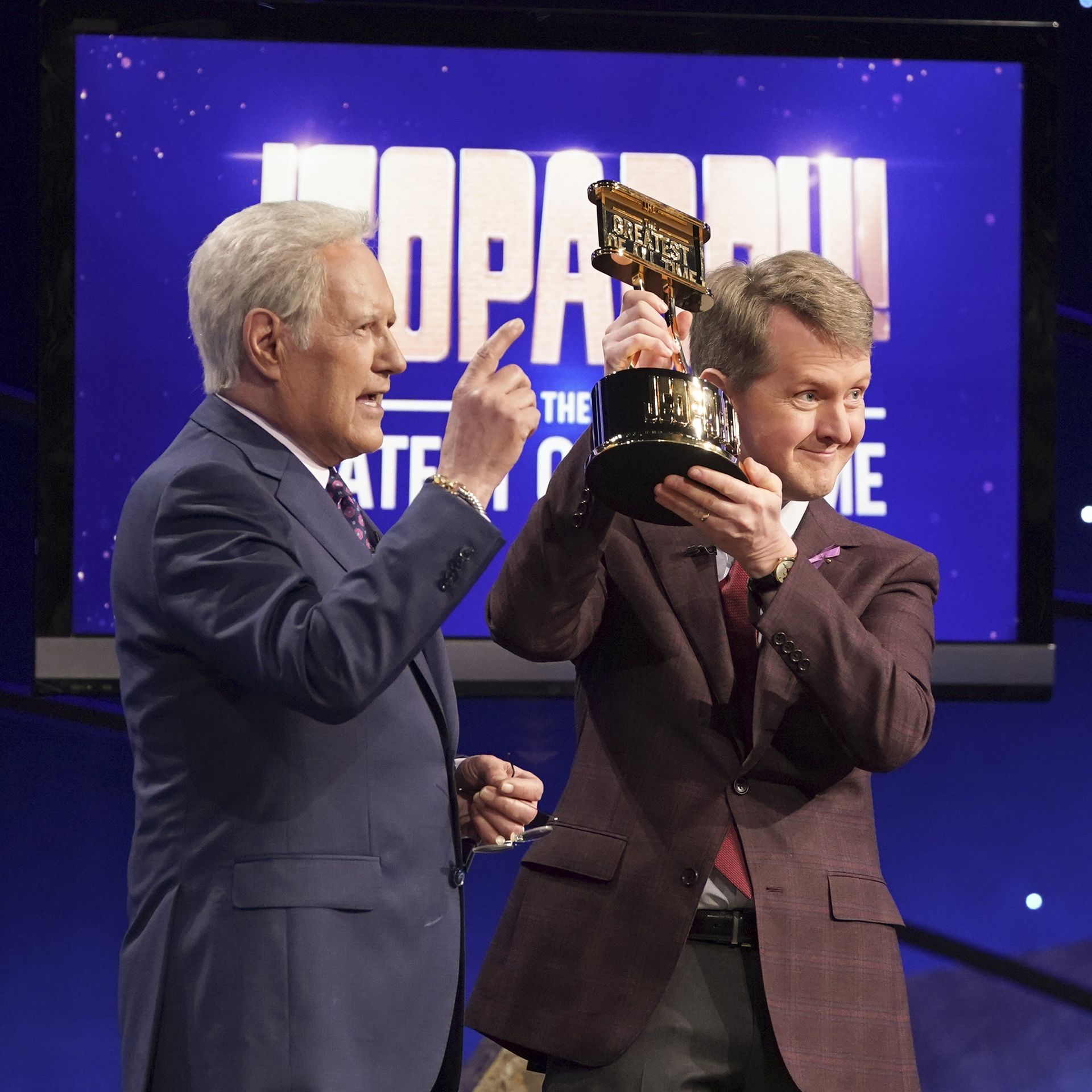 Alex Trebek and Ken Jennings hold up a trophy at  JEOPARDY! The Greatest of All Time