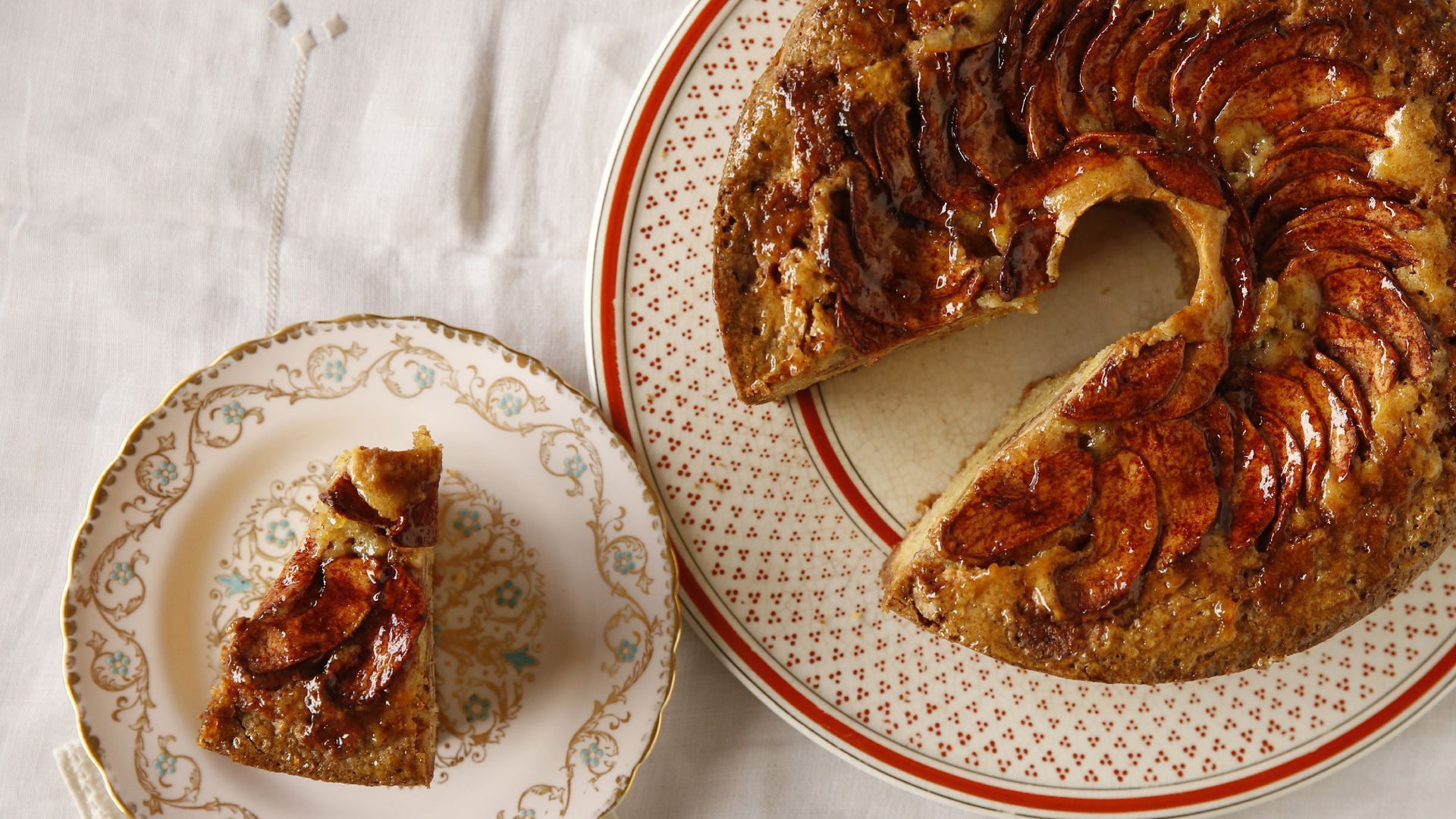A slice of apple cake pictured next to the whole