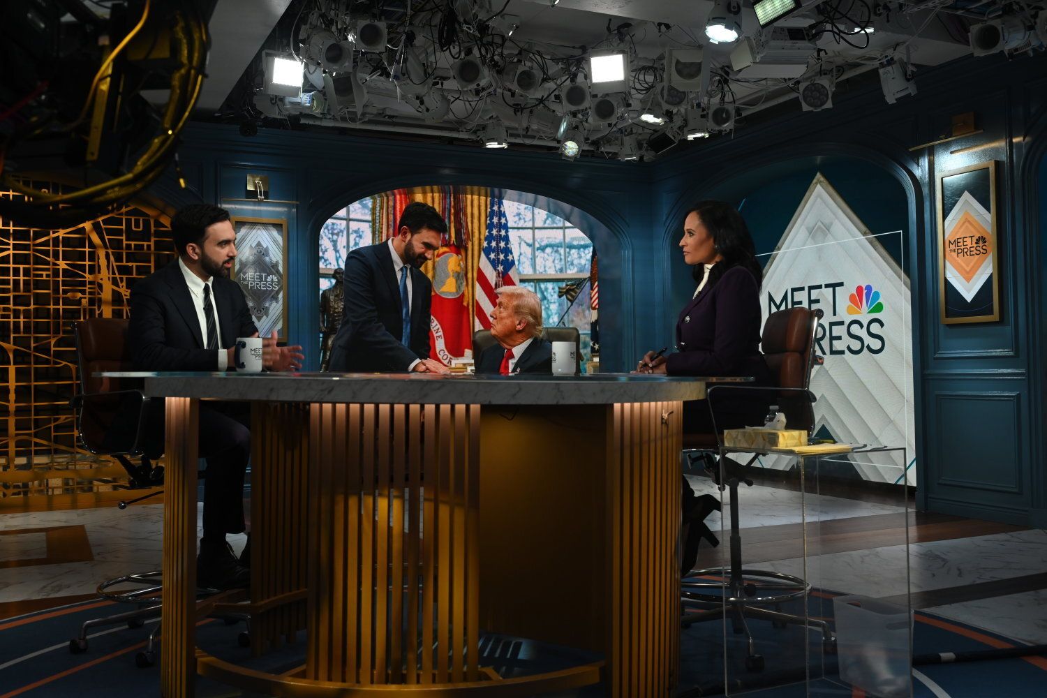 Television studio with Mamdani and Welker seated around a circular table under bright lights. "MEET THE PRESS" logos are visible in the background.