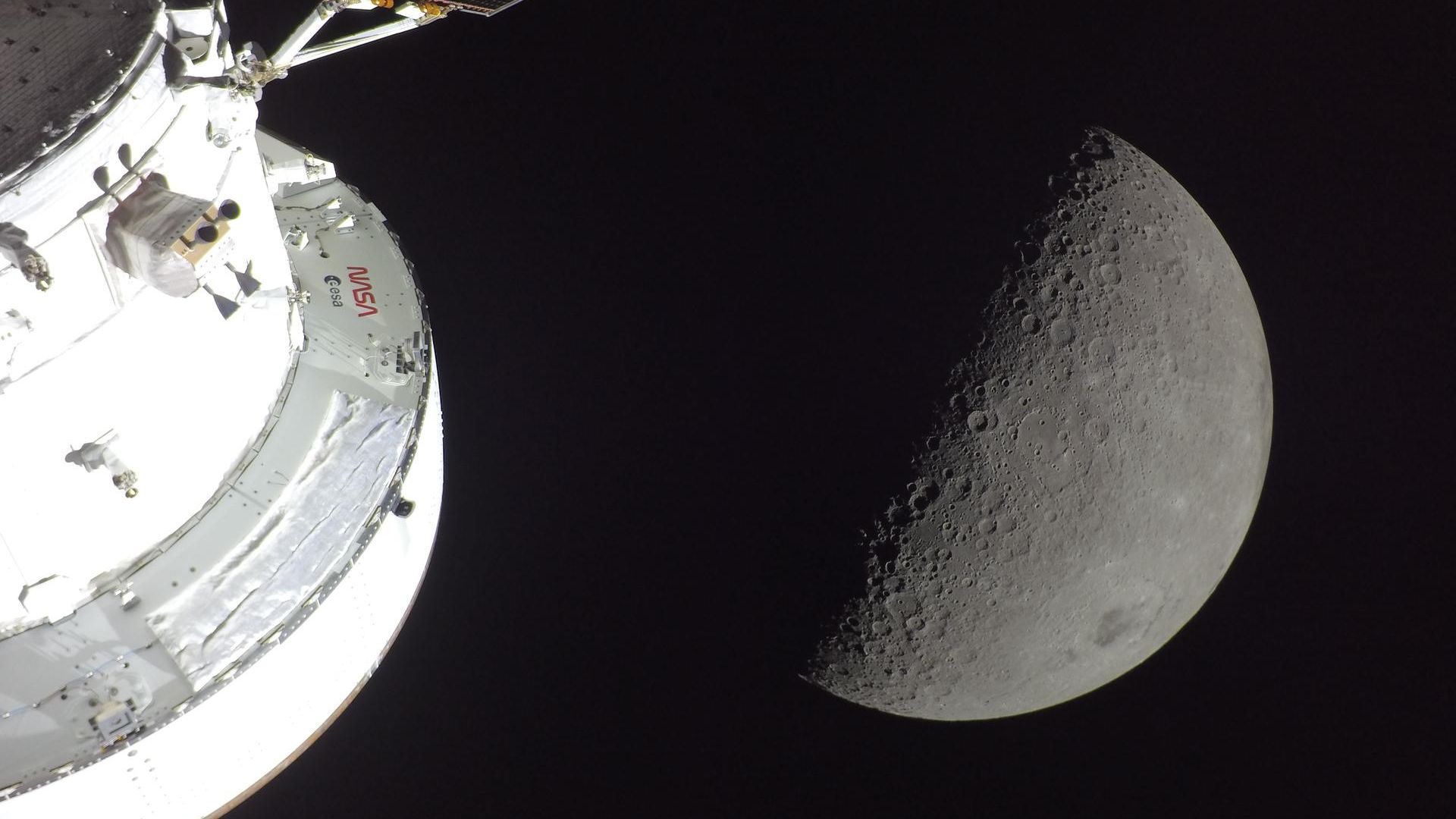 White NASA space shuttle orbiter hull on the left, with a large crescent Moon against the dark backdrop of space.