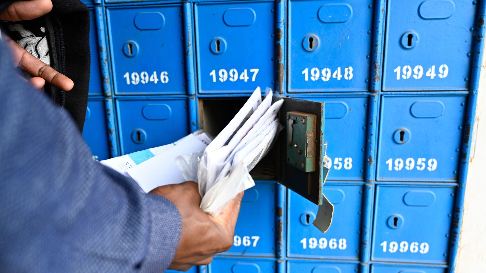 Photo of a man retrieving letters from a mailbox