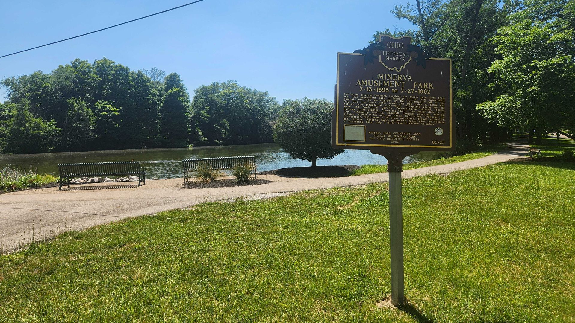 A historical marker for "Minerva Amusement Park" in front of a lake. 