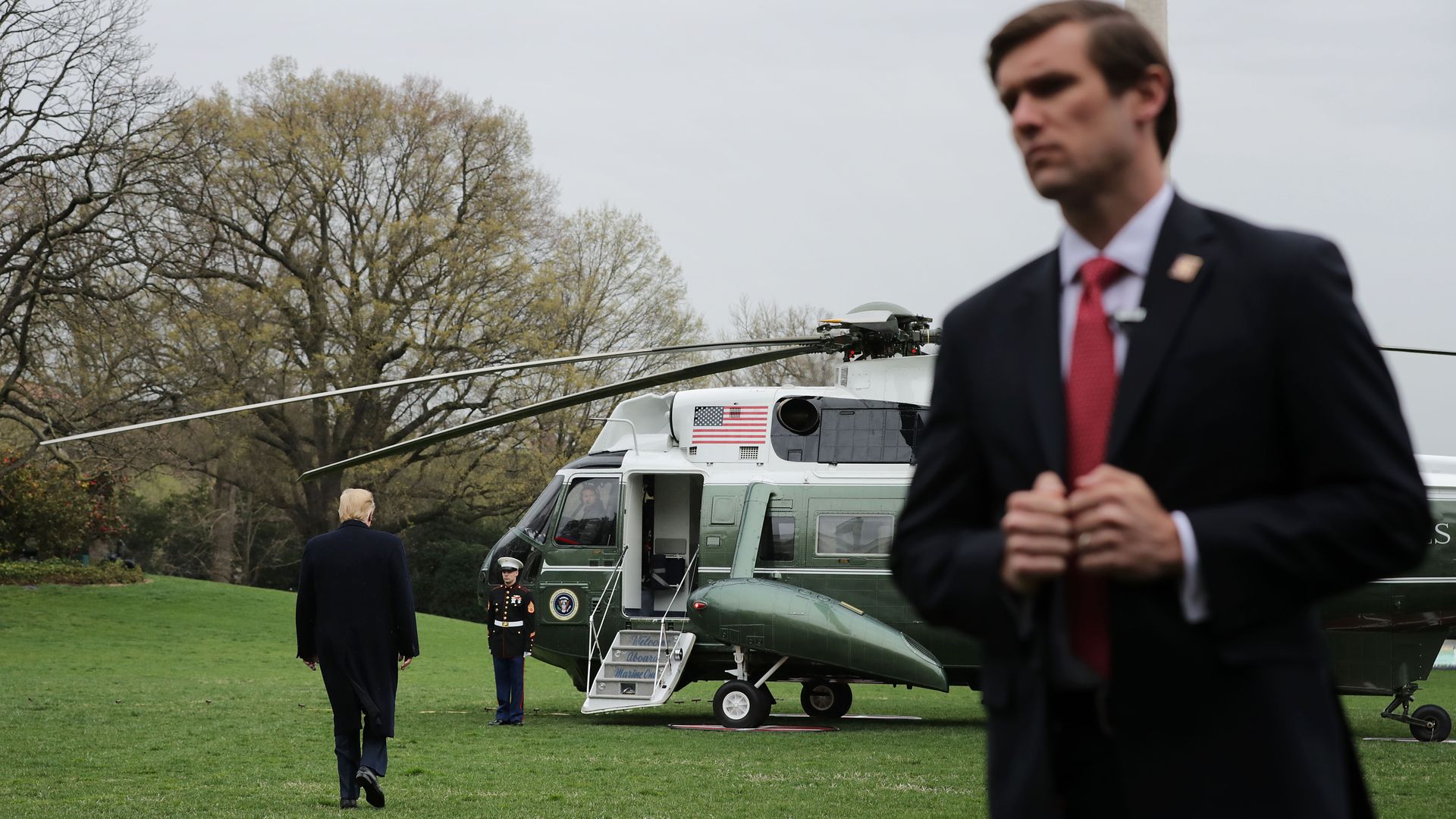 A U.S. Secret Service agent stands watch as President Donald Trump walks across the South Lawn before boarding Marine One at the White House.