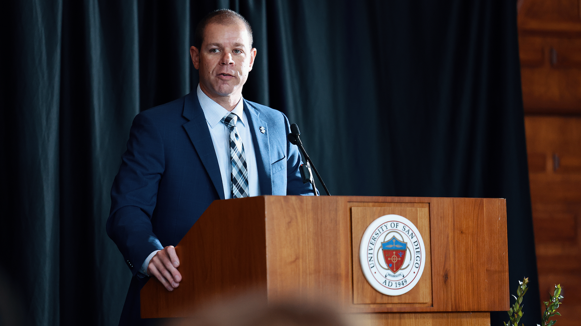A man in a blue suit speaks at a podium.