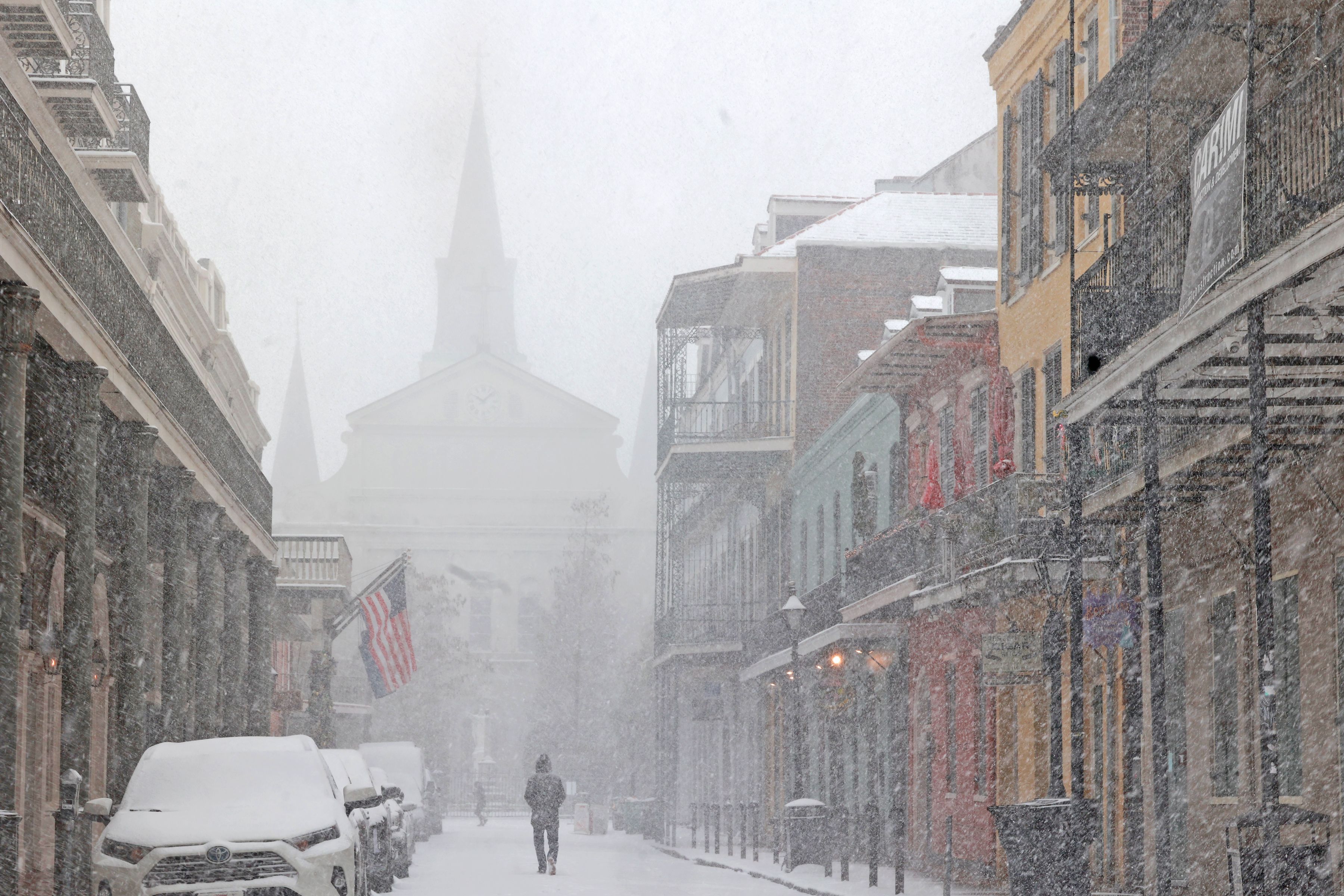 A snowy street in the French Quarter with the St. Louis Cathedral in the background.