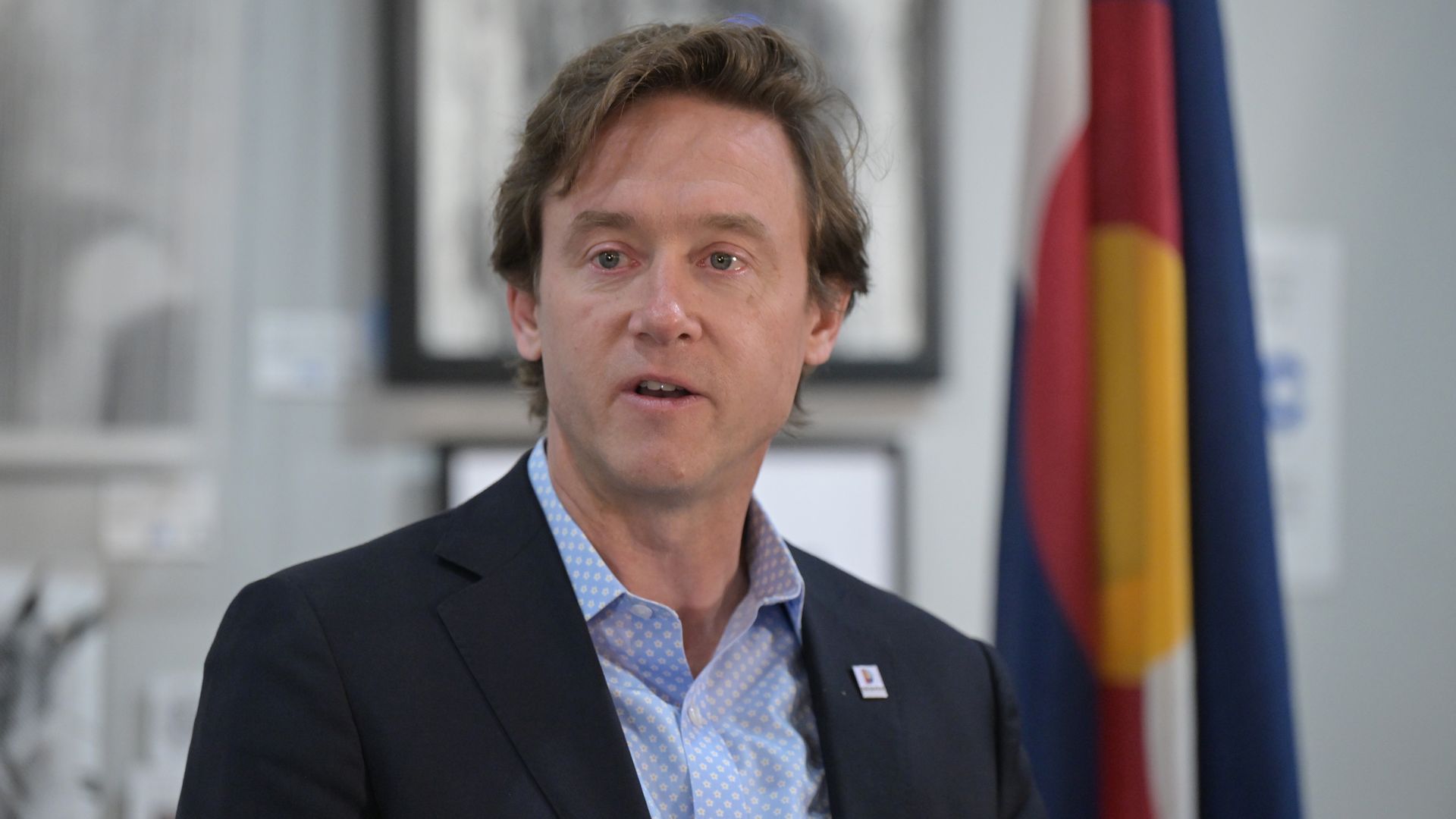 A man in a blazer and light shirt speaks. 