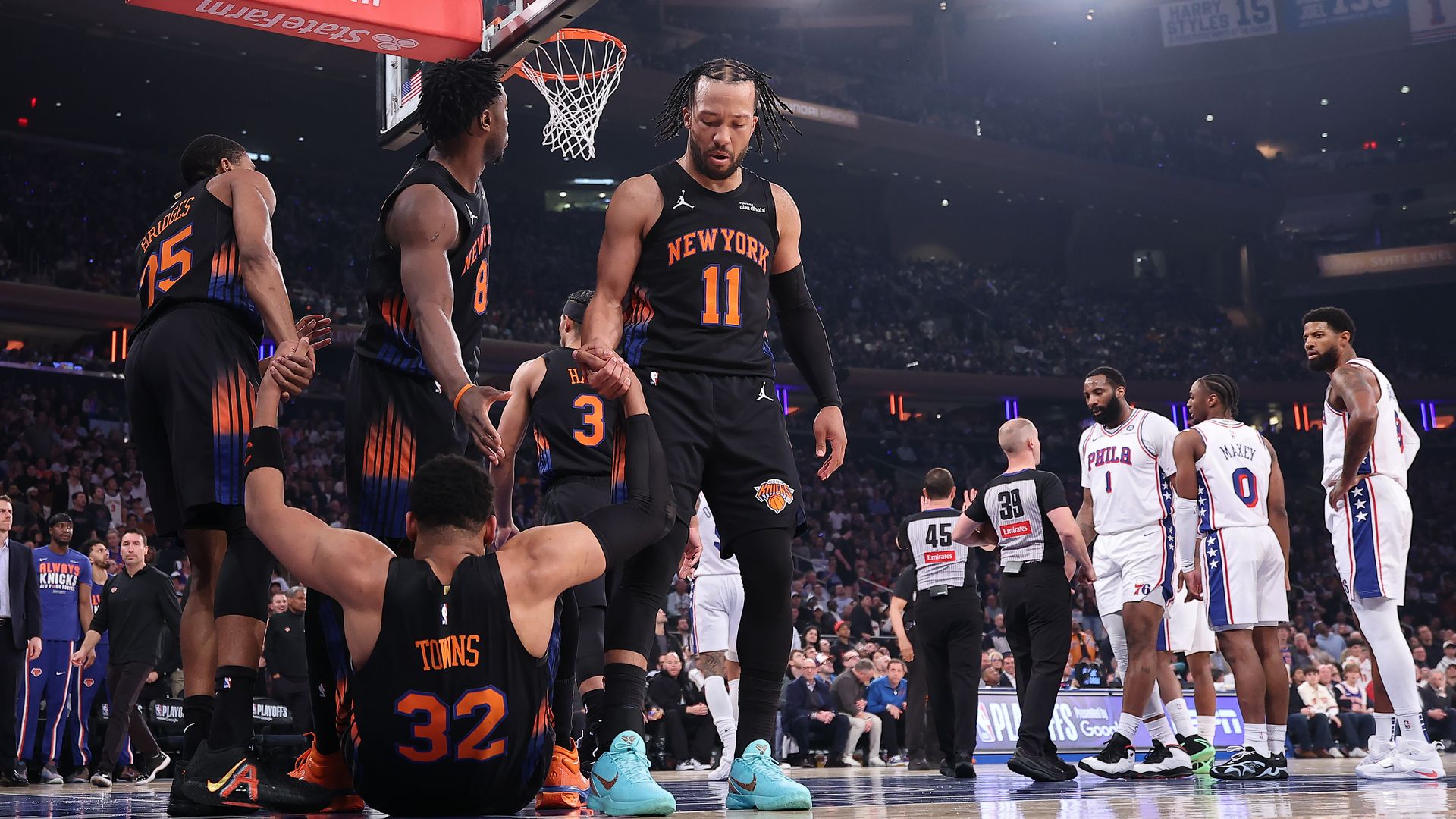 The Knicks' Karl-Anthony Towns is helped to his feet by teammate Mikal Bridges and Jalen Brunson.