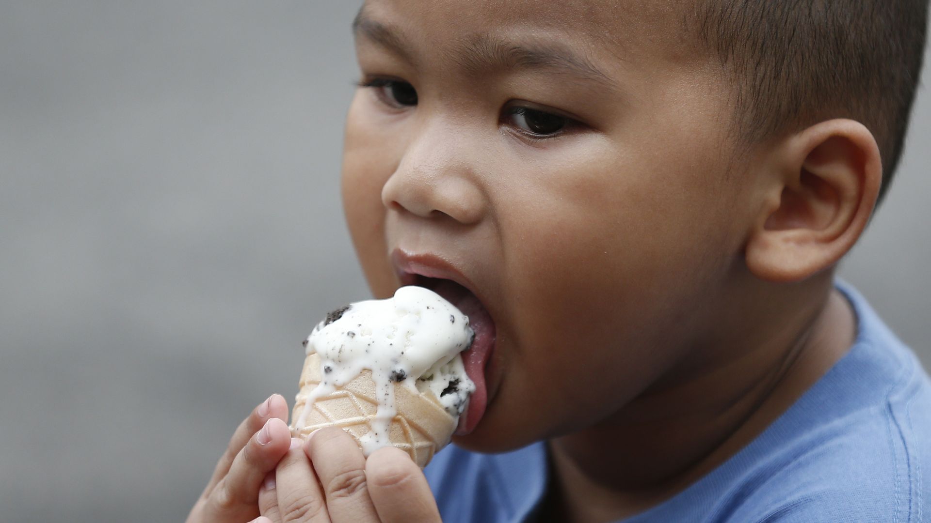 In this image, a toddler eats an ice cream cone