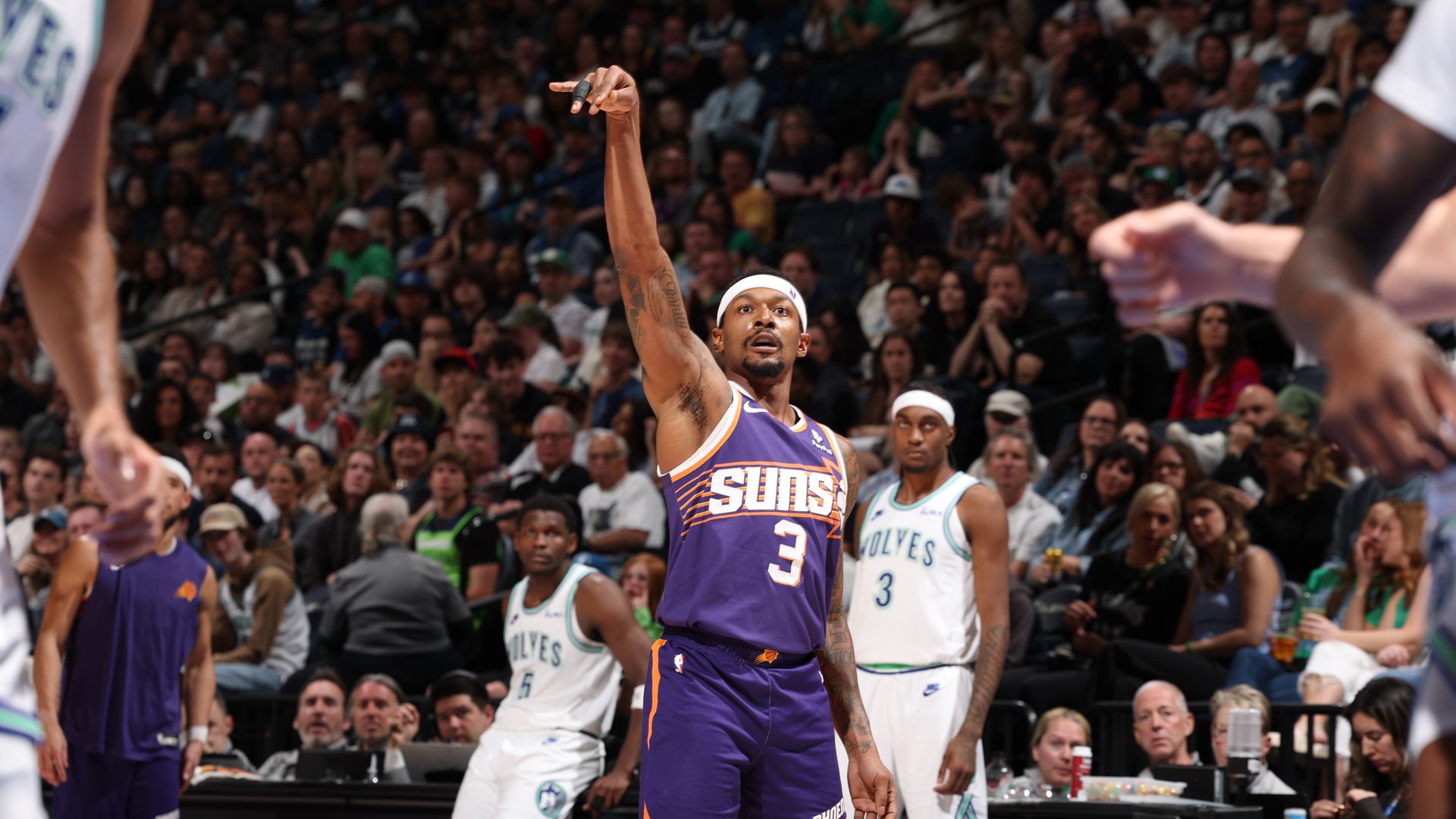 A basketball player holds his hand in the air in a shooting motion. 