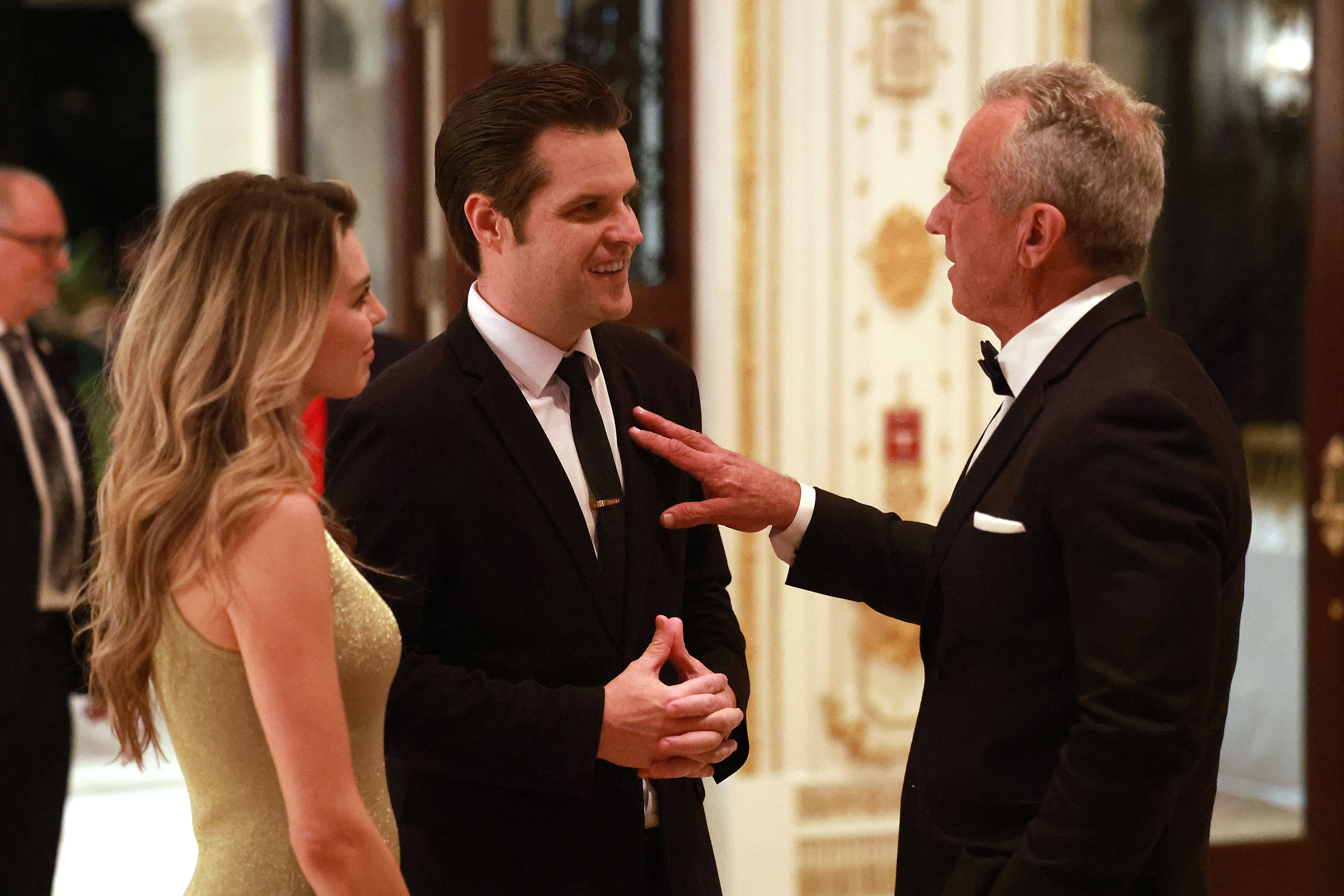 PALM BEACH, FLORIDA - NOVEMBER 14: Robert F. Kennedy Jr. (R) talks with former U.S. Rep. Matt Gaetz and his wife Ginger Luckey Gaetz at the America First Policy Institute Gala held at Mar-a-Lago on November 14, 2024 in Palm Beach, Florida. President-elect Donald Trump has been announcing a number of