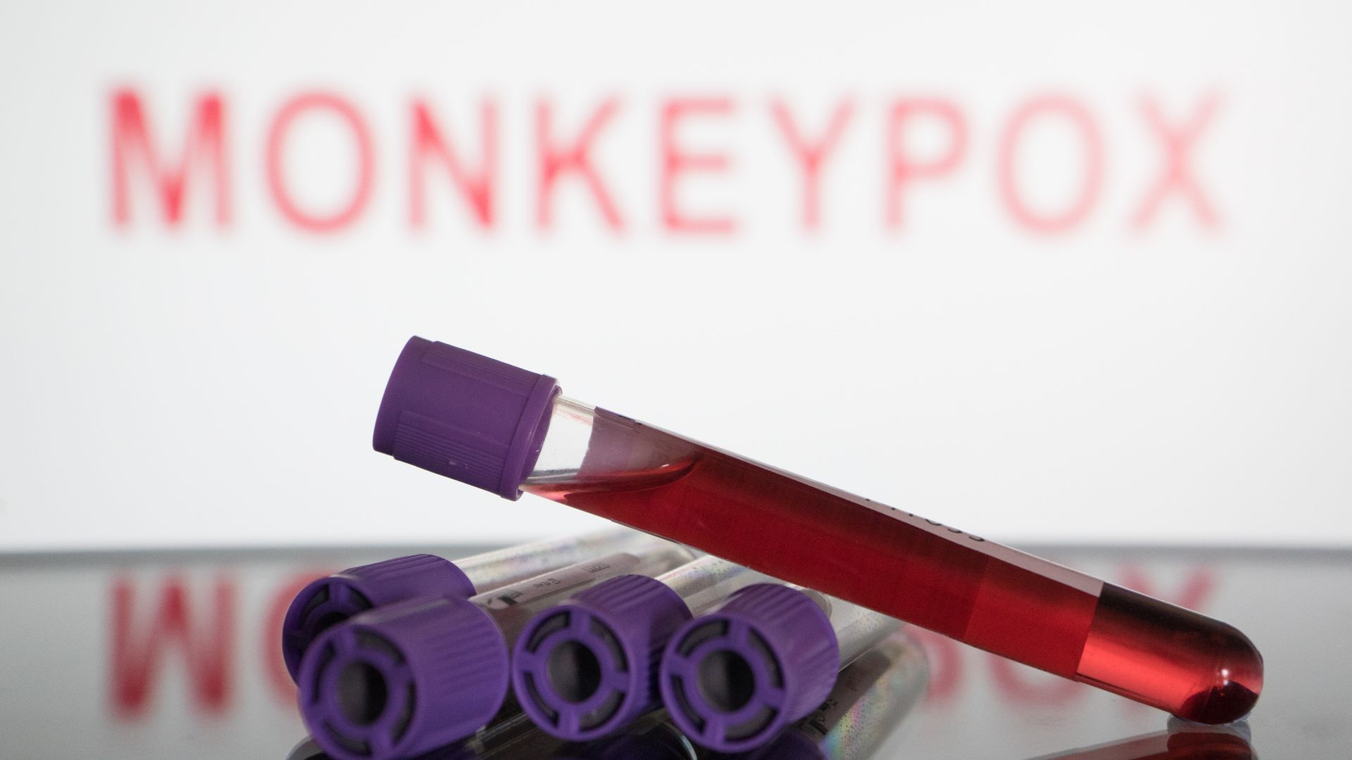 Photo illustration of blood test vials in front of a screen that says Monkeypox