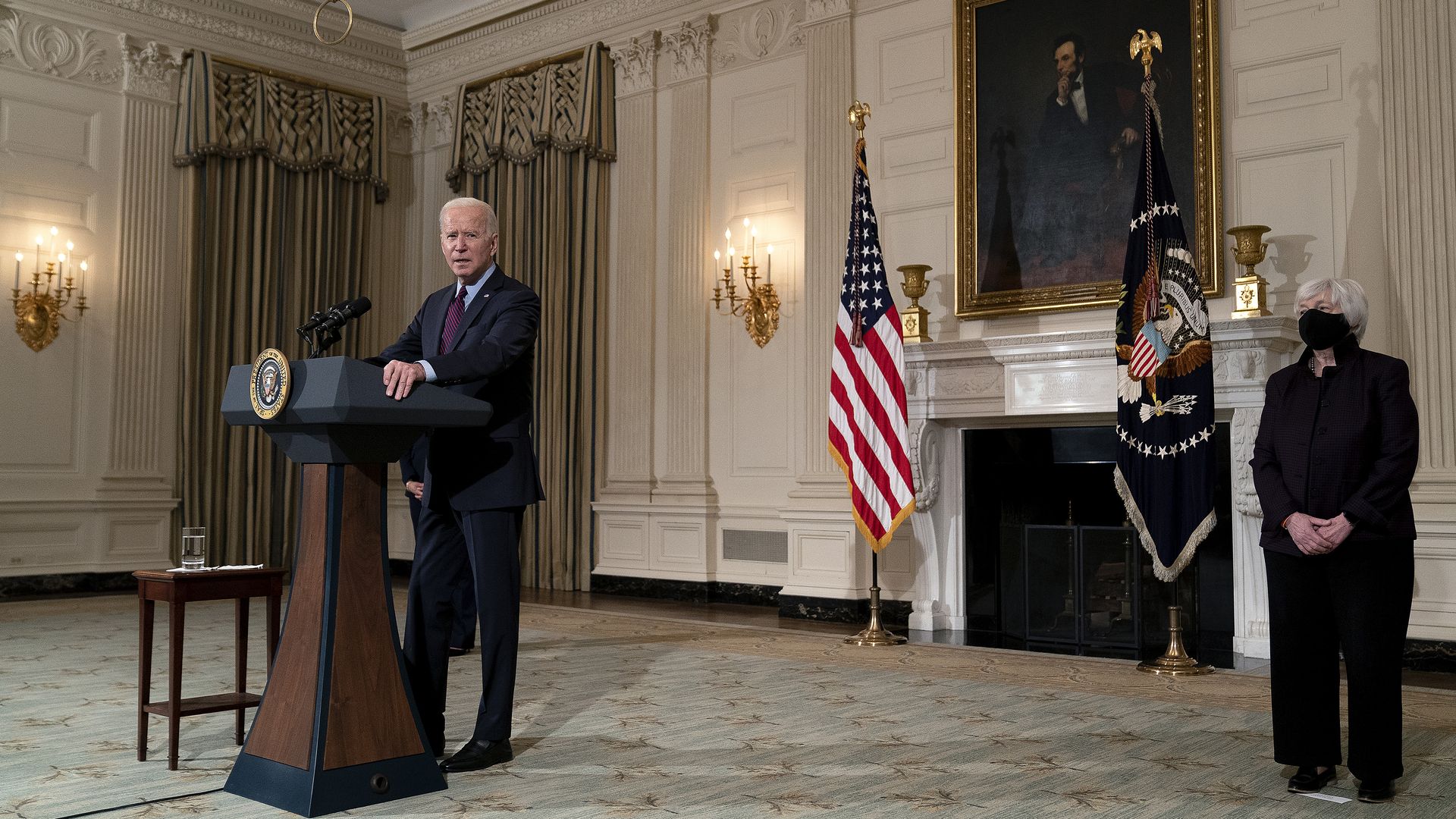 Biden at the podium speaking with Janet Yellen behind him 