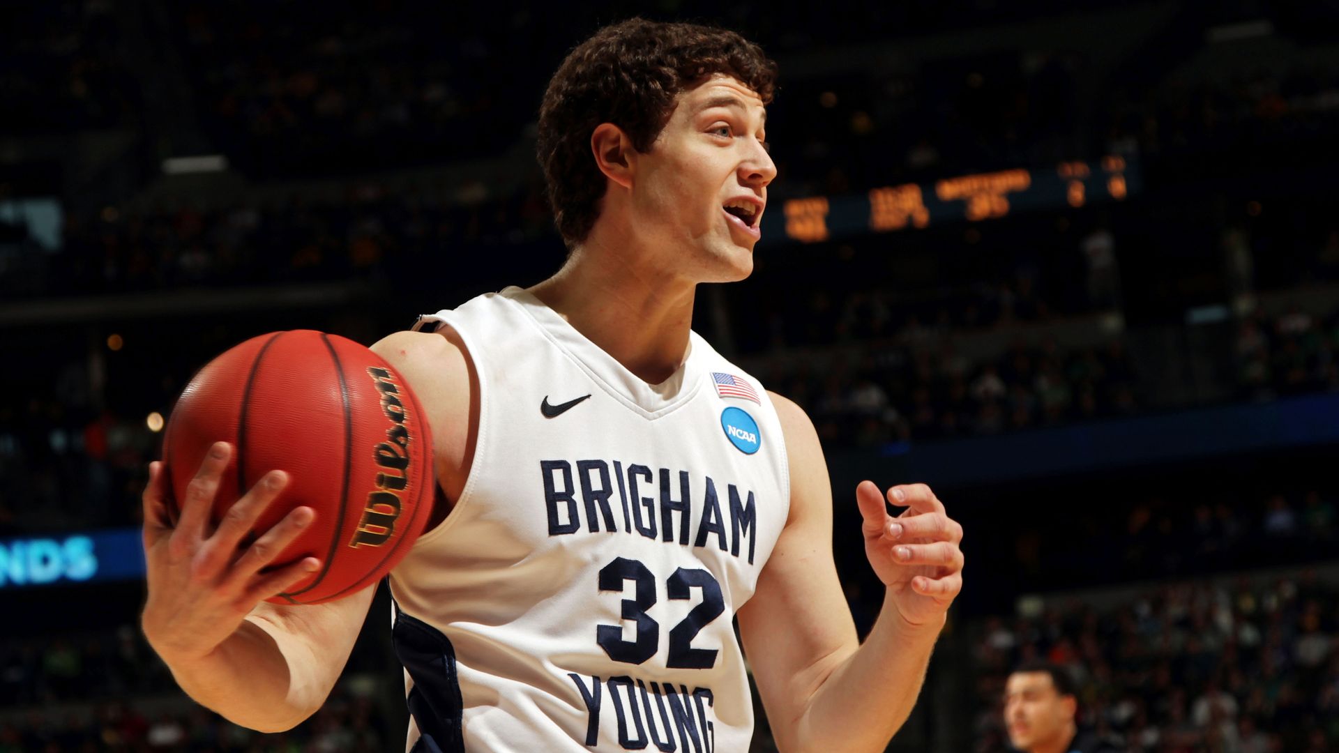 Basketball player Jimmer Fredette wears a BYU jersey and holds a ball as he reacts to a call during a game. 