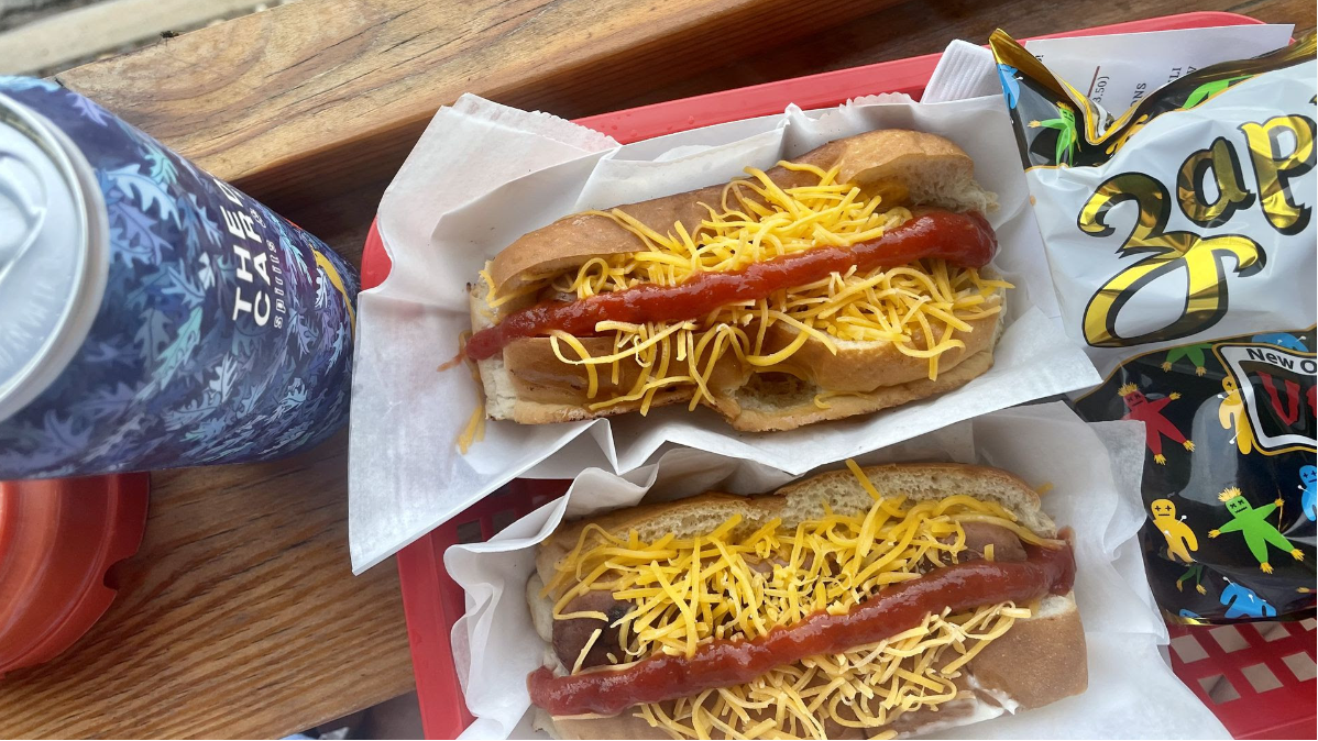Two hot dogs covered in cheese and ketchup. 