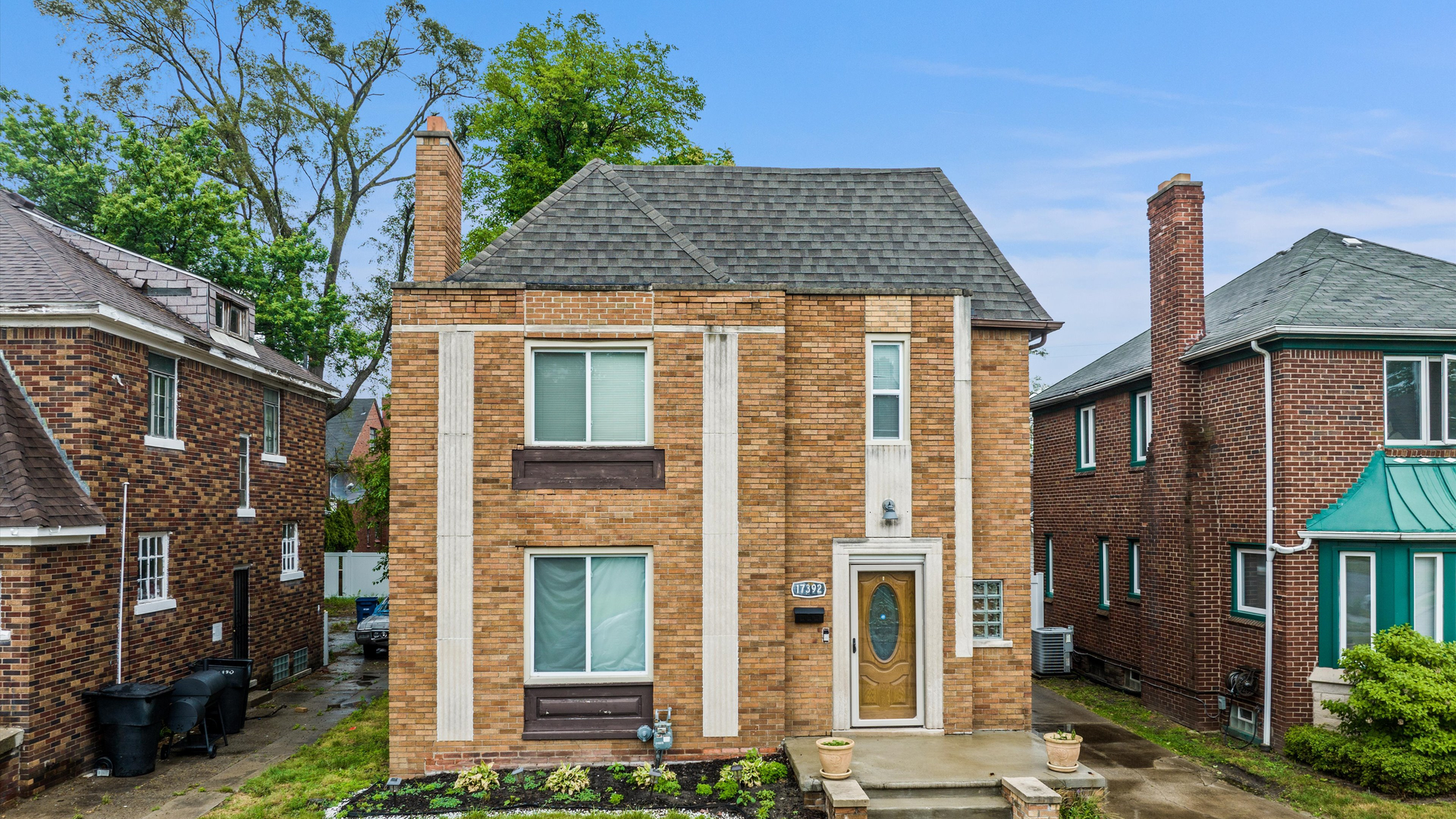 The home's front exterior is shown with a wide facade, brick and a wooden front door.