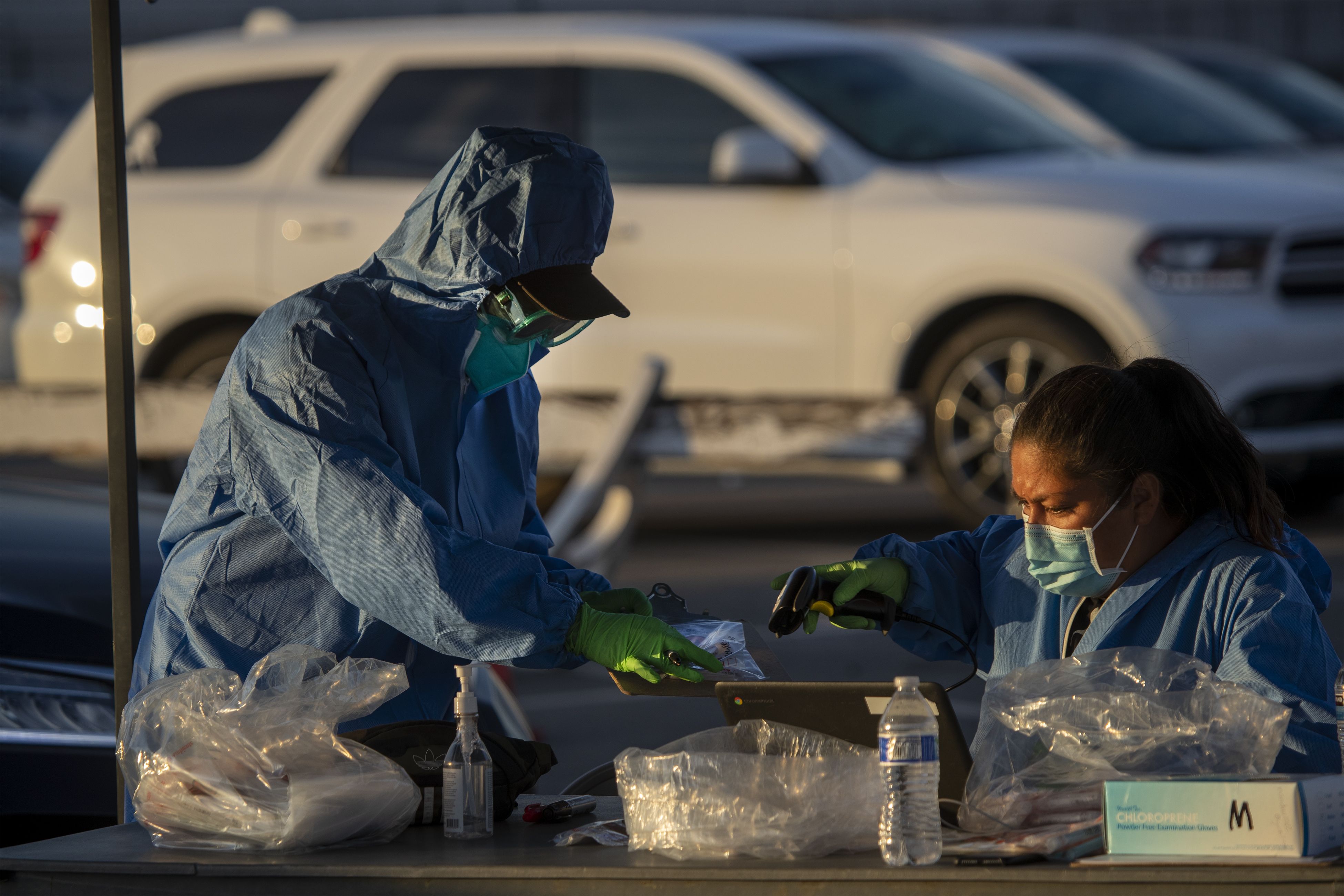Health care workers prepare COVID-19 tests to hand out to long lines of subjects who self-administer the tests at Long Beach City College-Veterans Memorial Stadium on Wednesday, Dec. 9