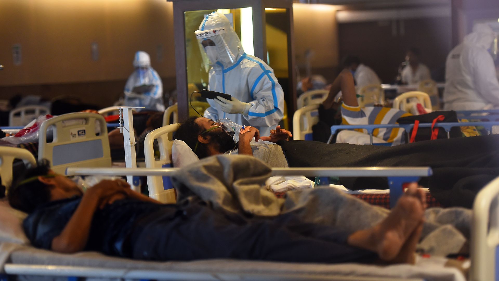 Picture of a health worker in protective gear helping a coronavirus patient